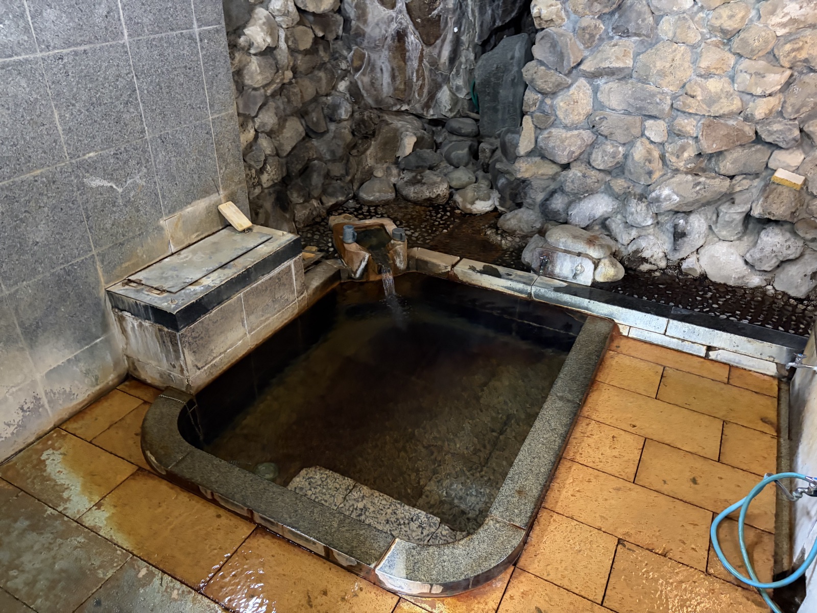 河原の湯 浴槽・石壁と黒タイル浴槽