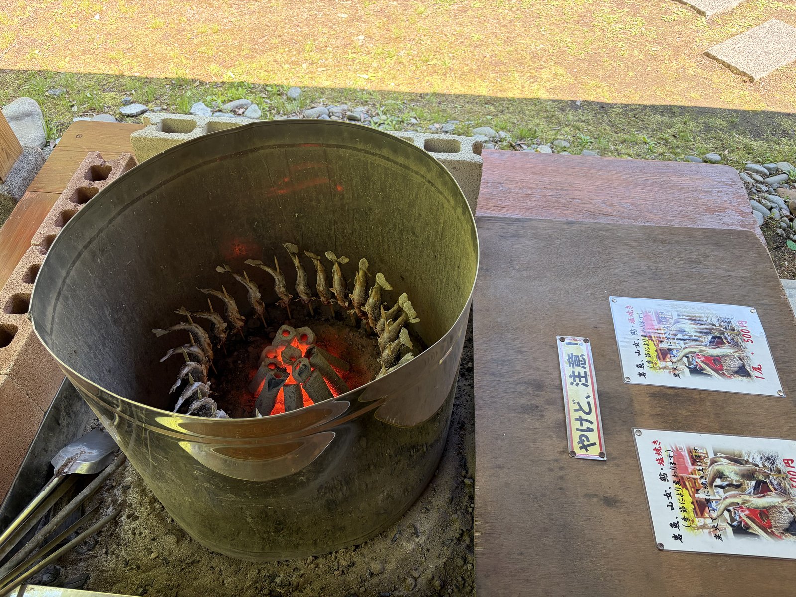 敷地内直売所の火鉢で川魚を塩焼きにしている様子
