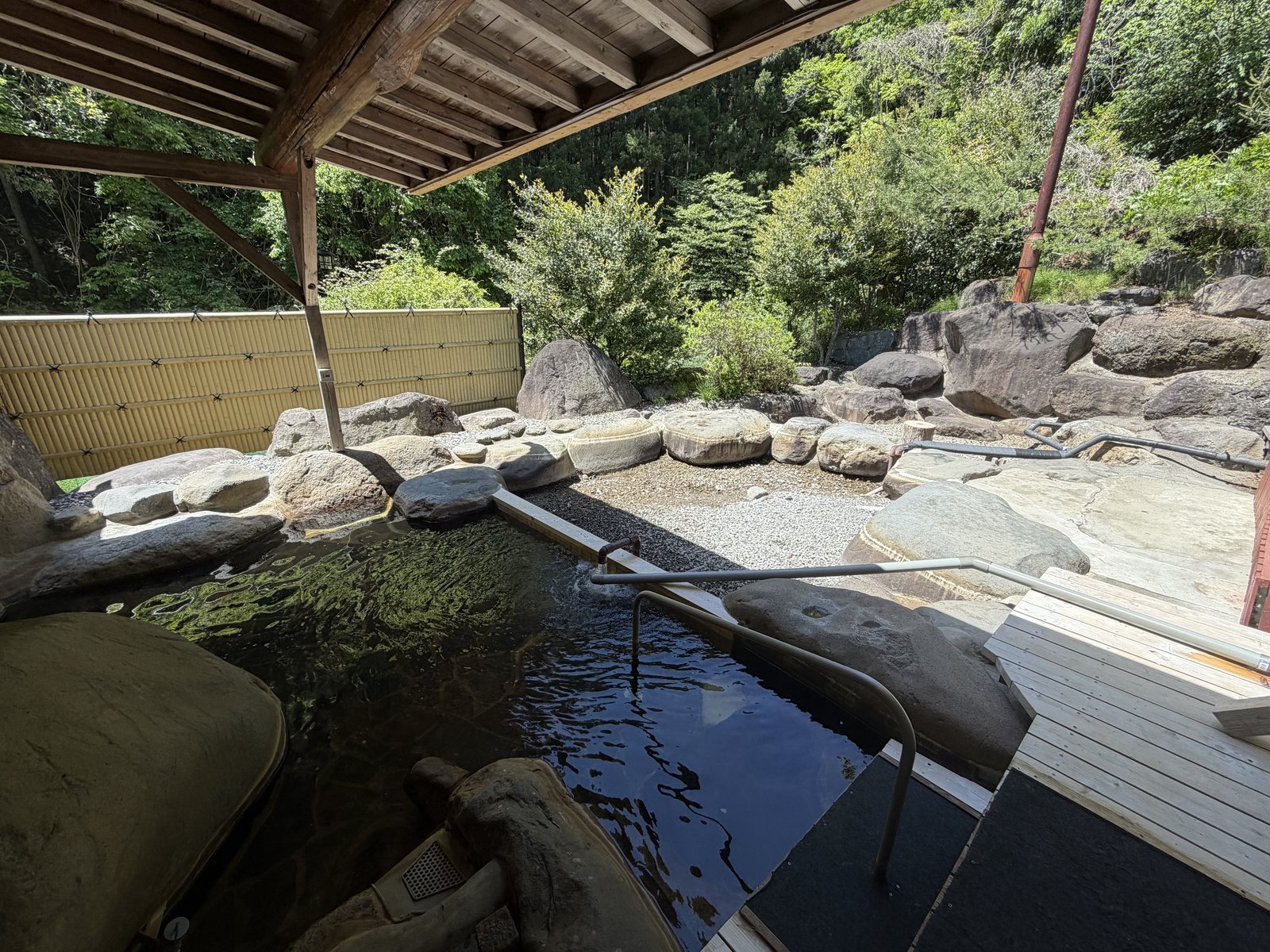 露天風呂全景・木造屋根・岩組・新緑バック
