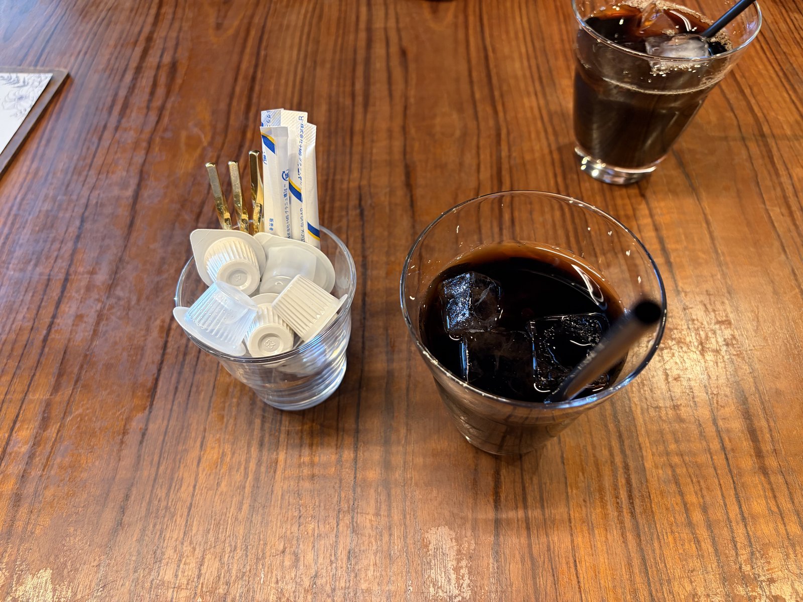 アイスコーヒー・木目の机・シンプルな盃グラス