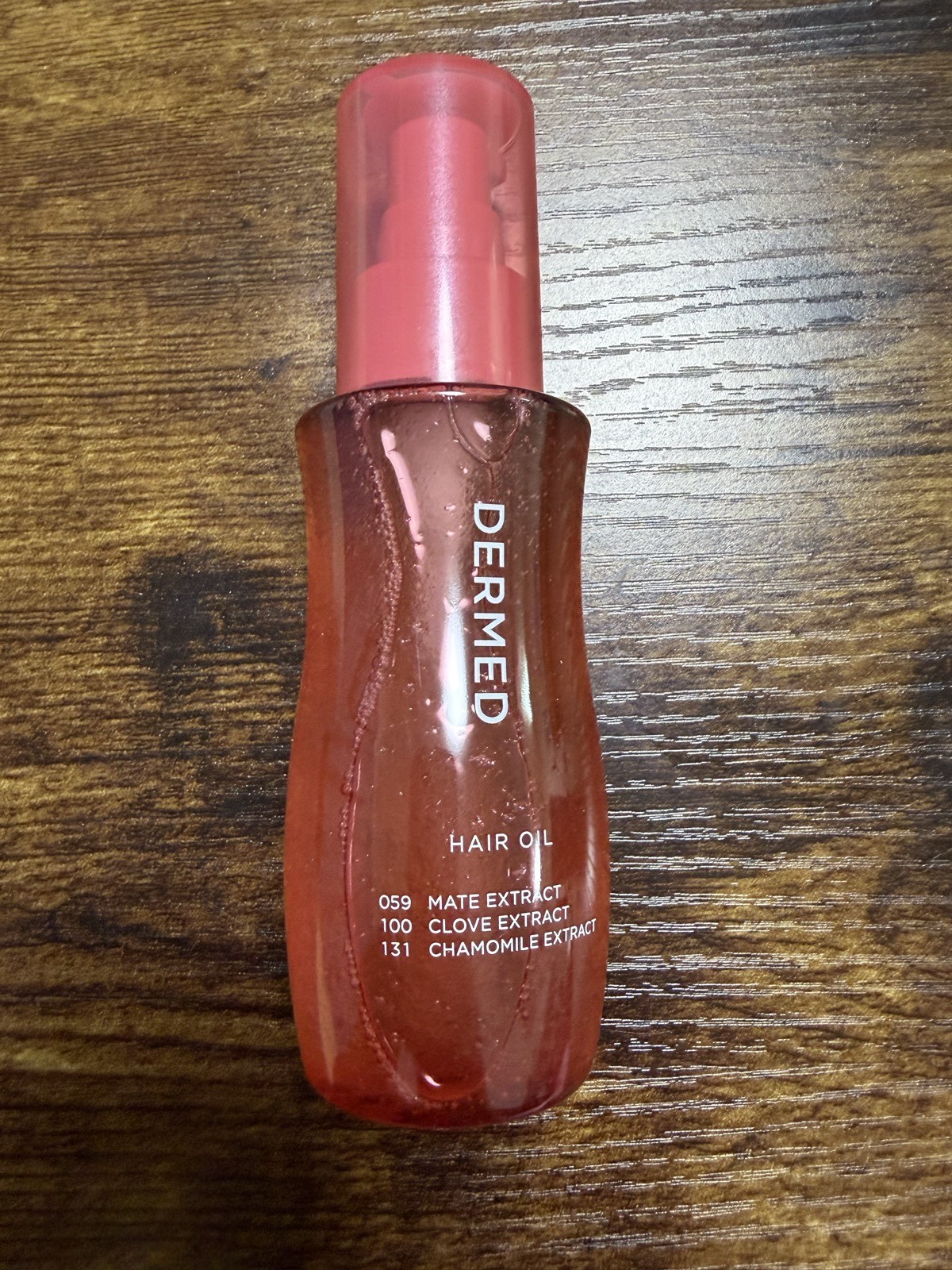DERMED ヘアオイル 100mL ピンク色のボトル、ロゴ周りに「059 MATE EXTRACT / 100 CLOVE EXTRACT / 131 CHAMOMILE EXTRACT」の3種植物エキス番号が並ぶ