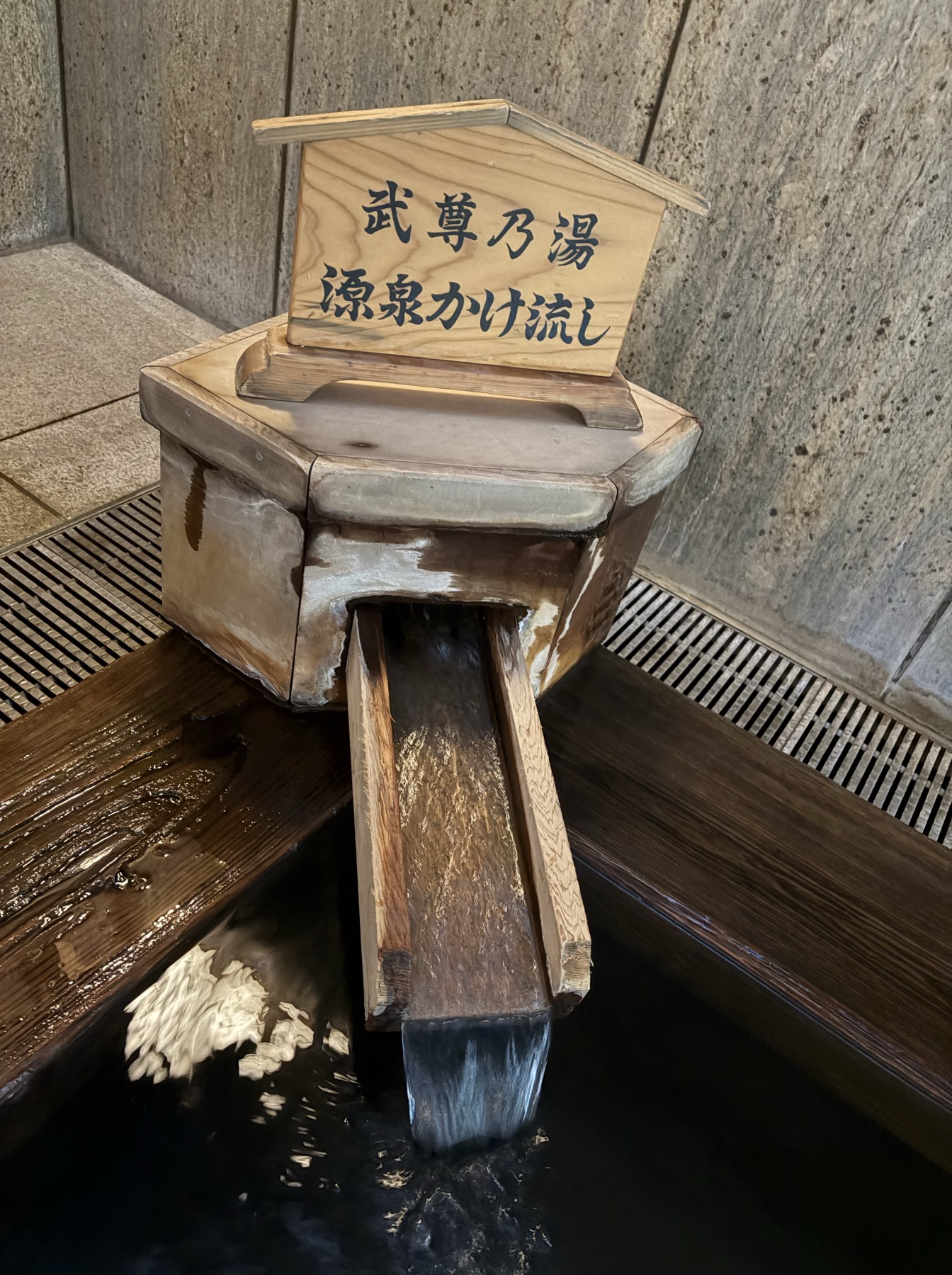 「武尊乃湯 源泉かけ流し」の木札と湯口