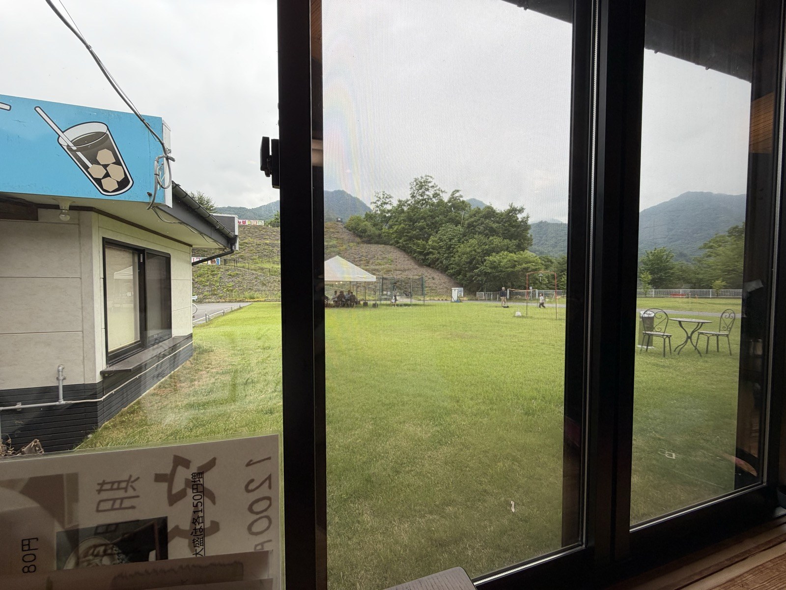 麦の香りの窓から見える芝生広場と山並み