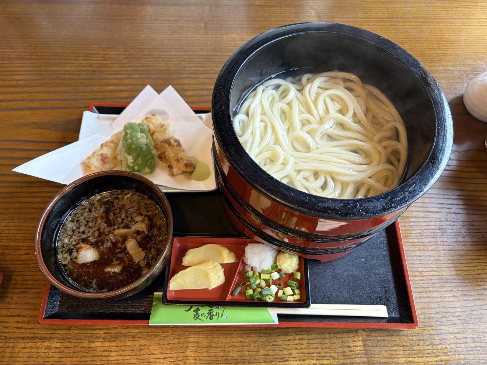 湯気の立つ釜揚げうどんと肉汁のつけ汁、天ぷら