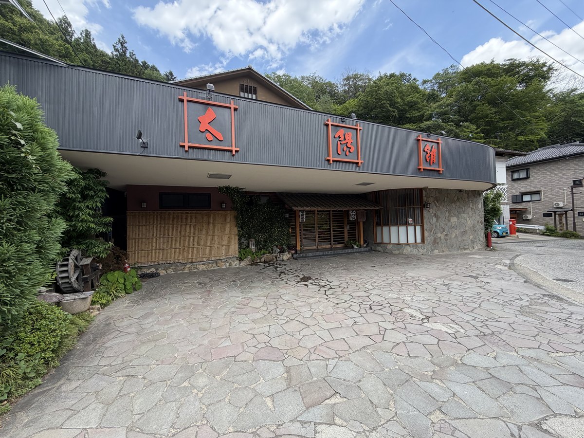 外観｜「太陽館」の赤い文字看板と石畳の車寄せ
