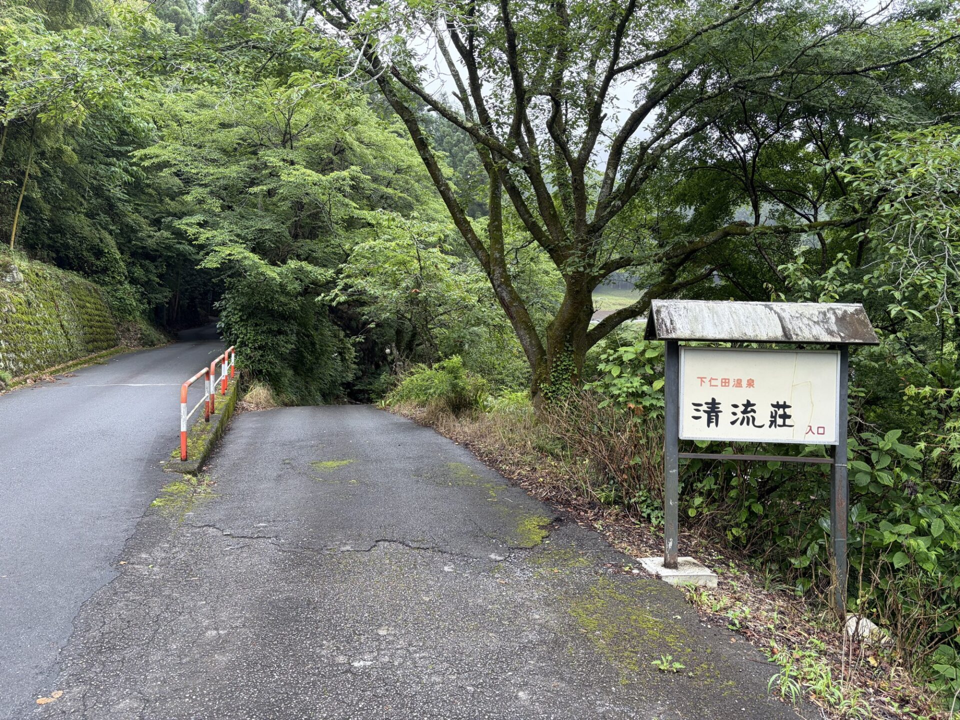 入口看板と山道（赤いガードレールの坂）