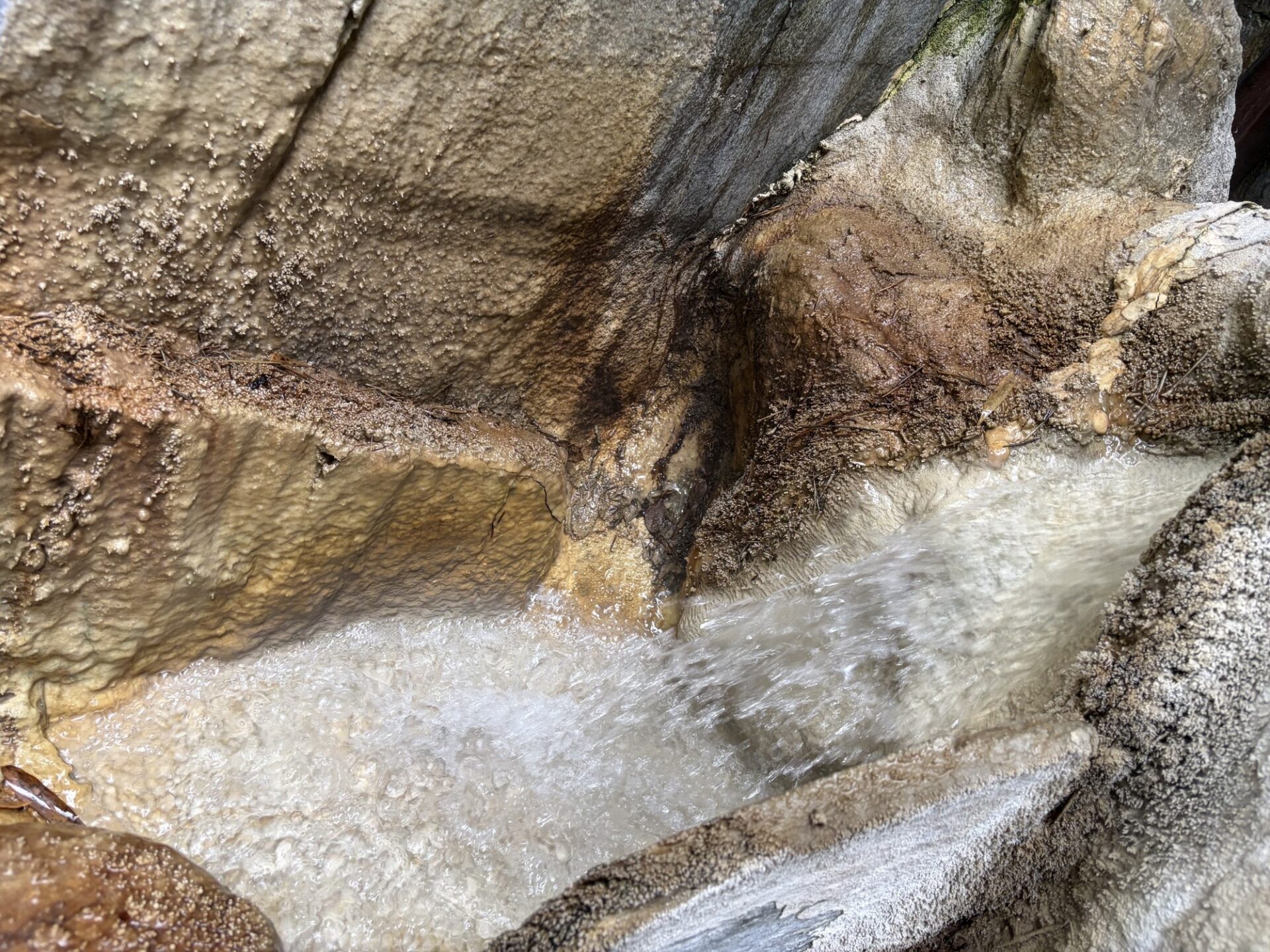 岩肌を流れる源泉と茶褐色の析出物
