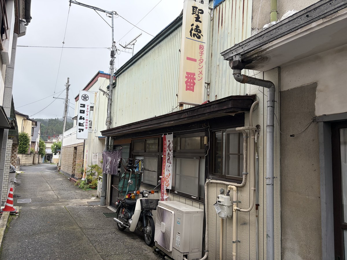 路地から見た餃子・タンメン一番の外観。縦看板と向かいのコロムビア