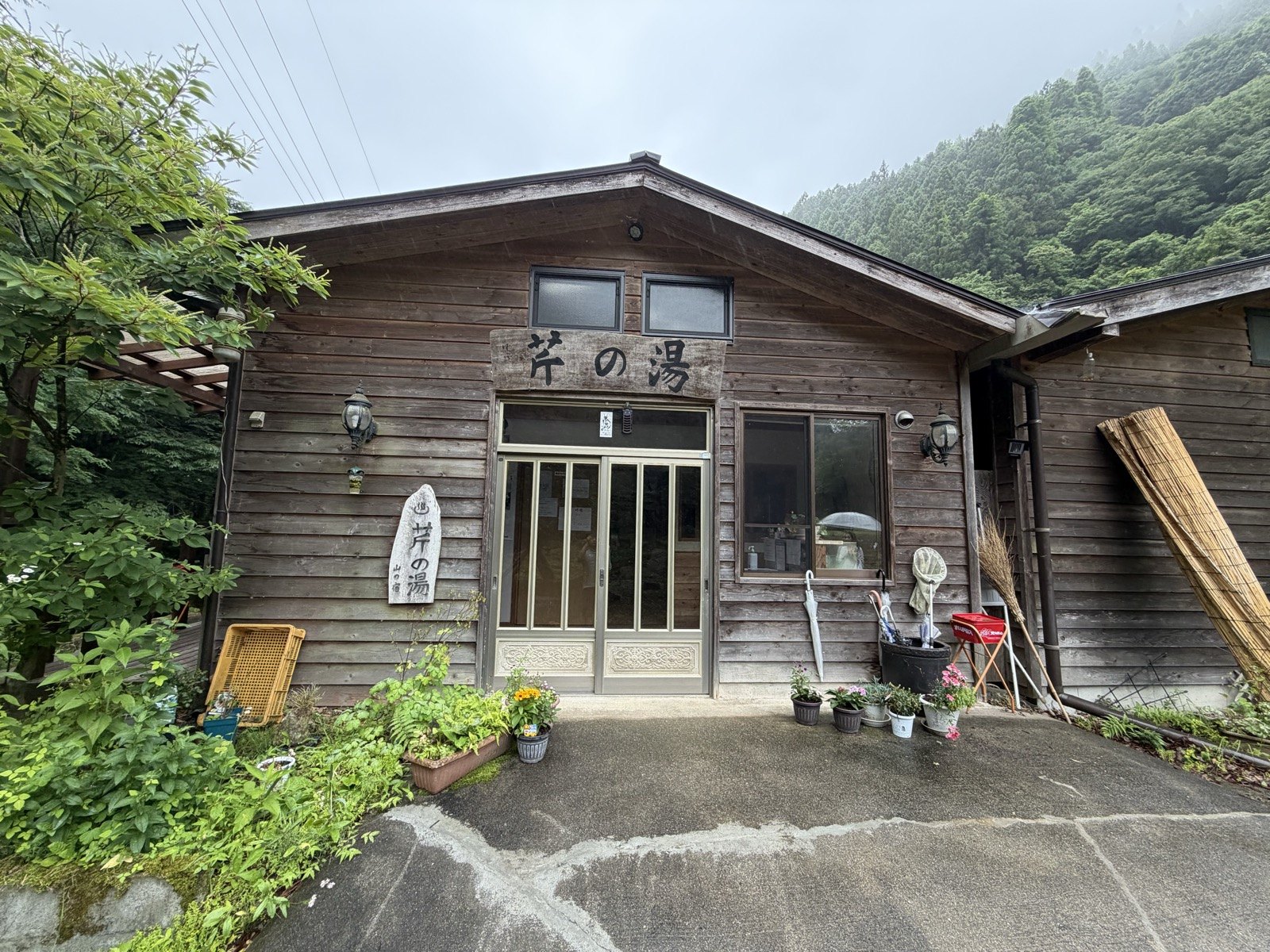 山を背負った木づくりの建物正面と「芹の湯」の木看板