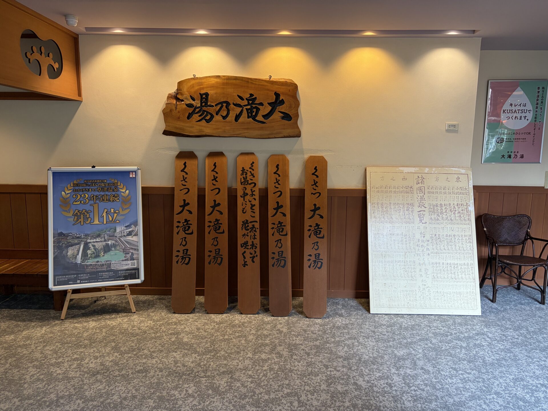 ロビー。草津温泉「にっぽんの温泉100選」23年連続1位の表彰ポスターと、大滝乃湯の彫り札