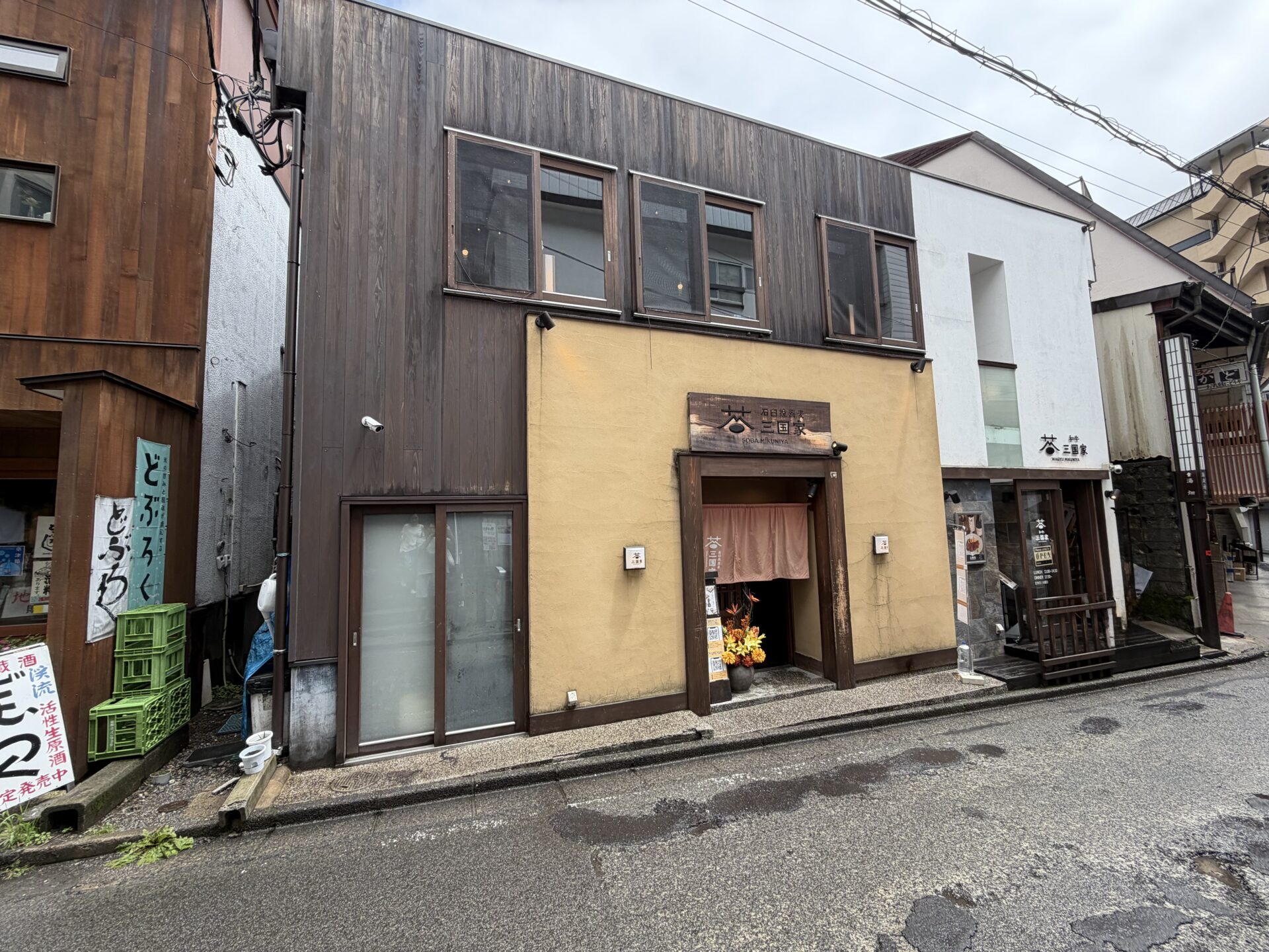 三国家の外観。湯畑エリアの細い坂道に立つ木造の店