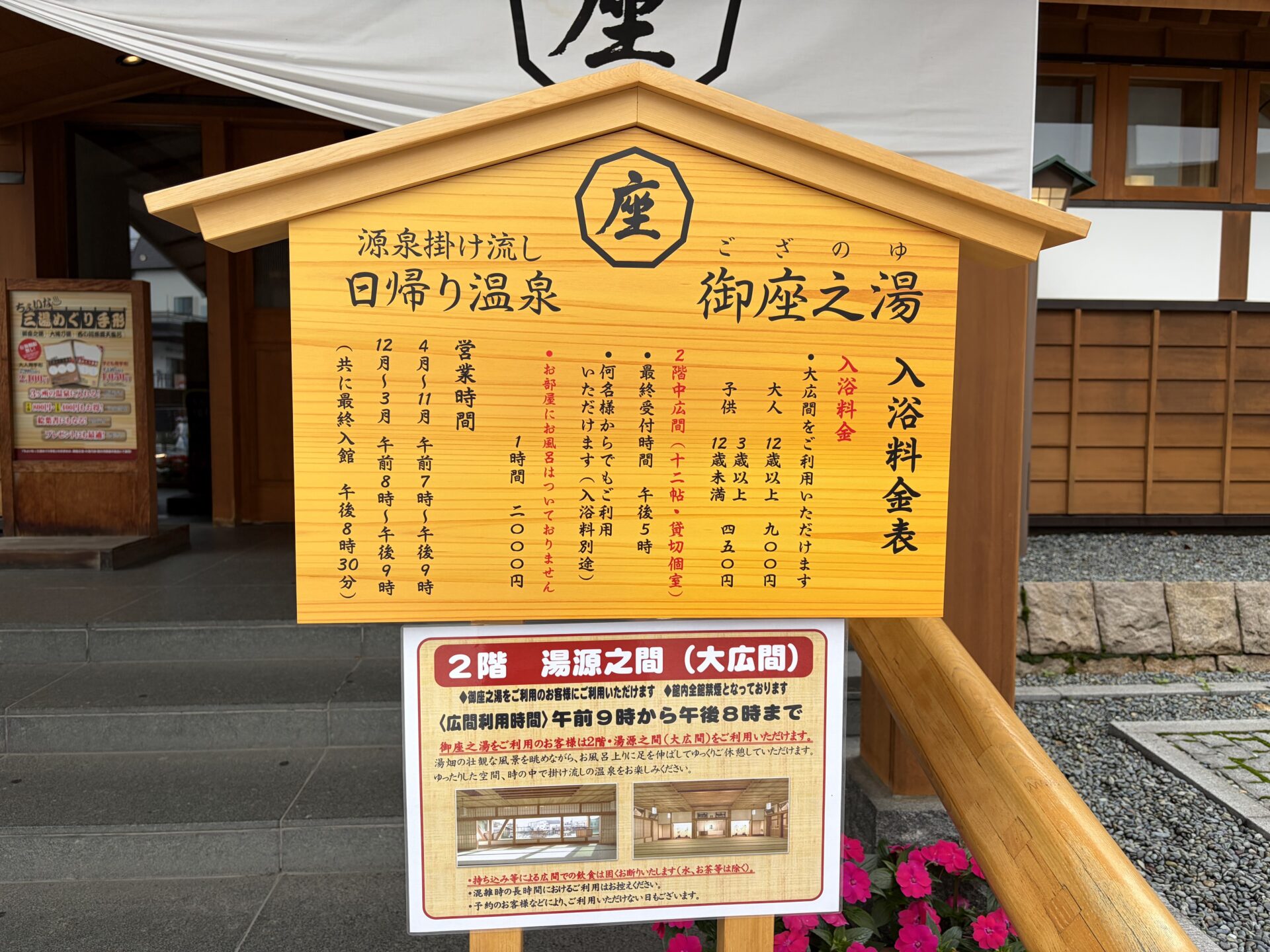 入口前の料金・営業時間の看板。「源泉掛け流し 日帰り温泉 御座之湯」