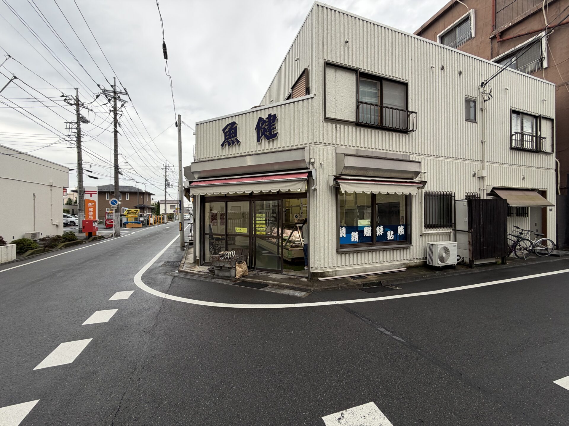 角地に建つ「魚健」の外観。2階壁面の青い看板