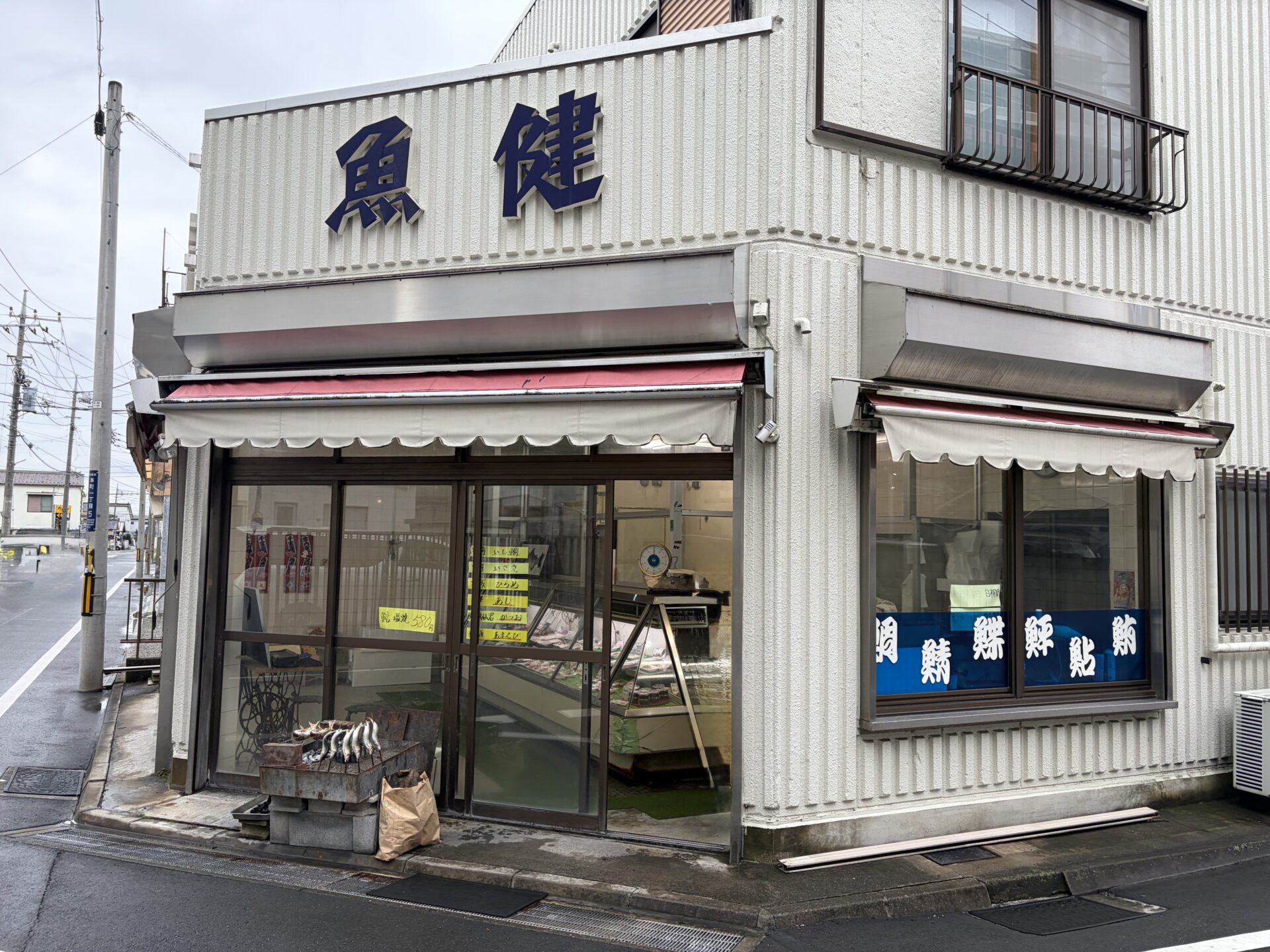 「魚健」の看板まわり。窓に並ぶ魚へんの文字