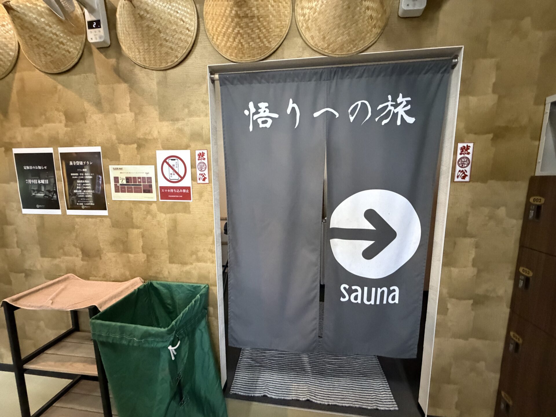 入口の暖簾。「悟りへの旅」の下に sauna への矢印が伸びる