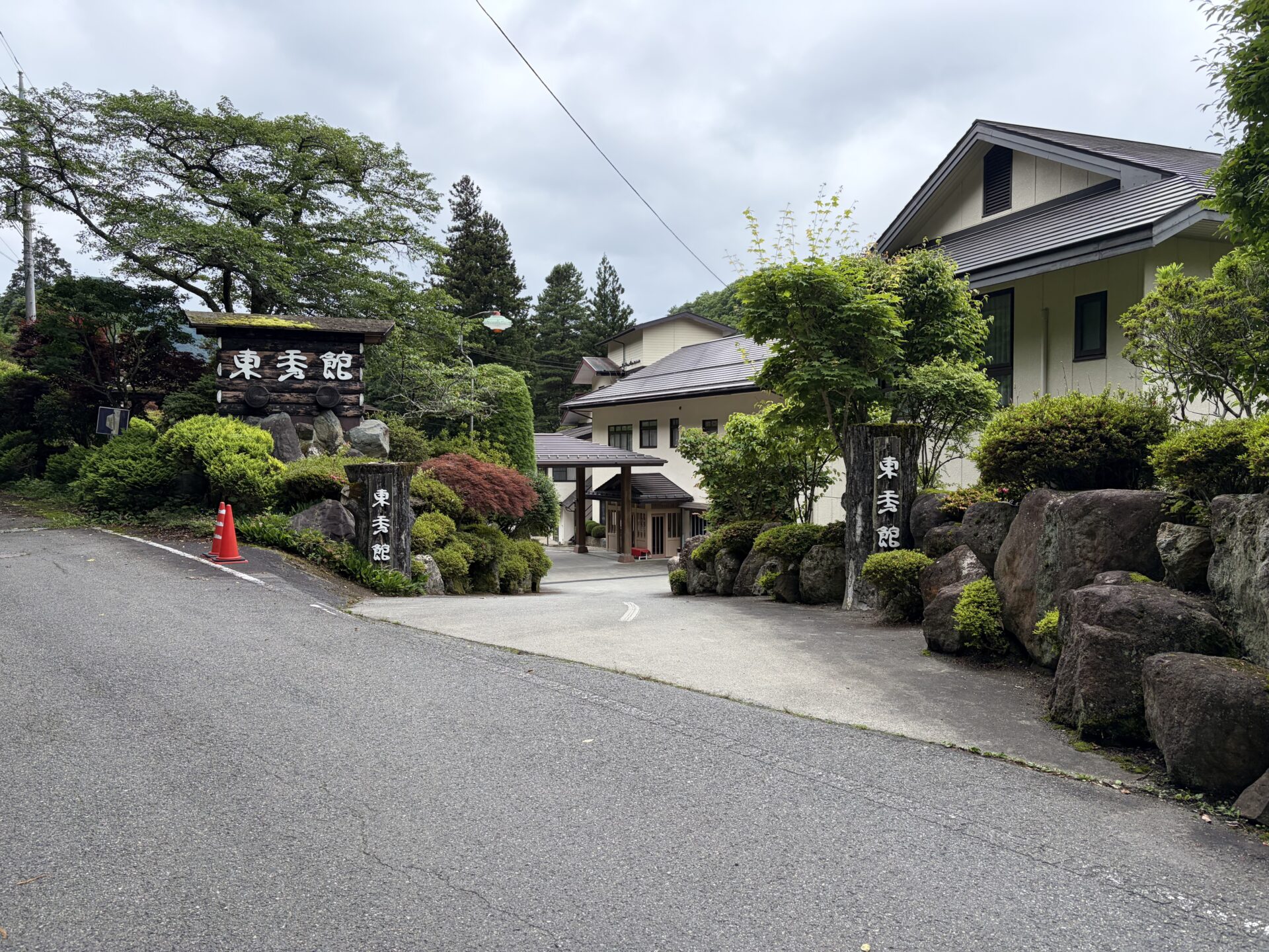 東秀館の外観。「東秀館」の看板石碑と和風の玄関、まわりは手入れされた緑