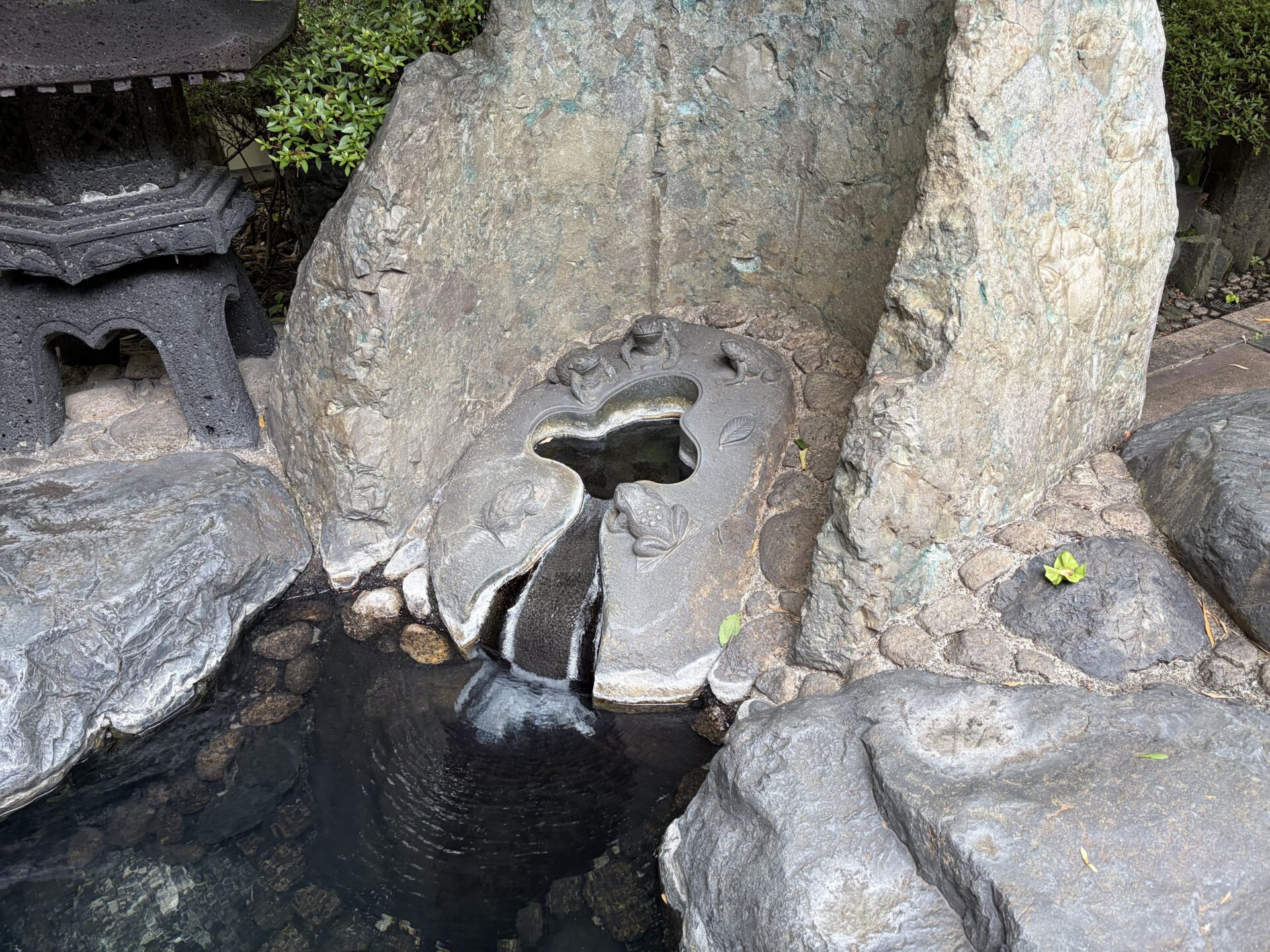 野天風呂の石の湯口。花を彫った石から湯が静かに流れ落ちる