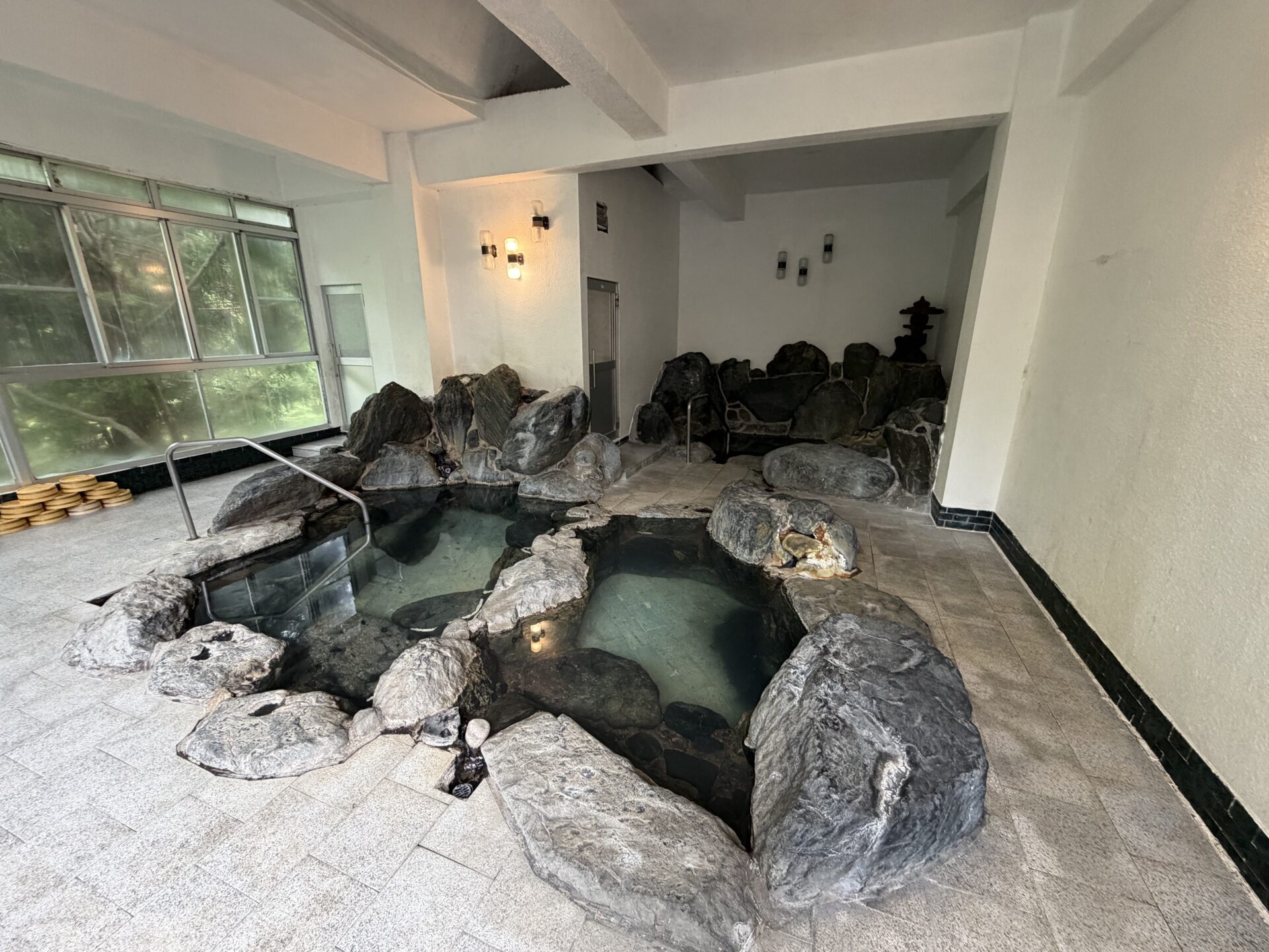 大浴場「仙涯乃湯」。岩で仕切られた温度違いの浴槽が並ぶ内湯、ガラス越しに緑