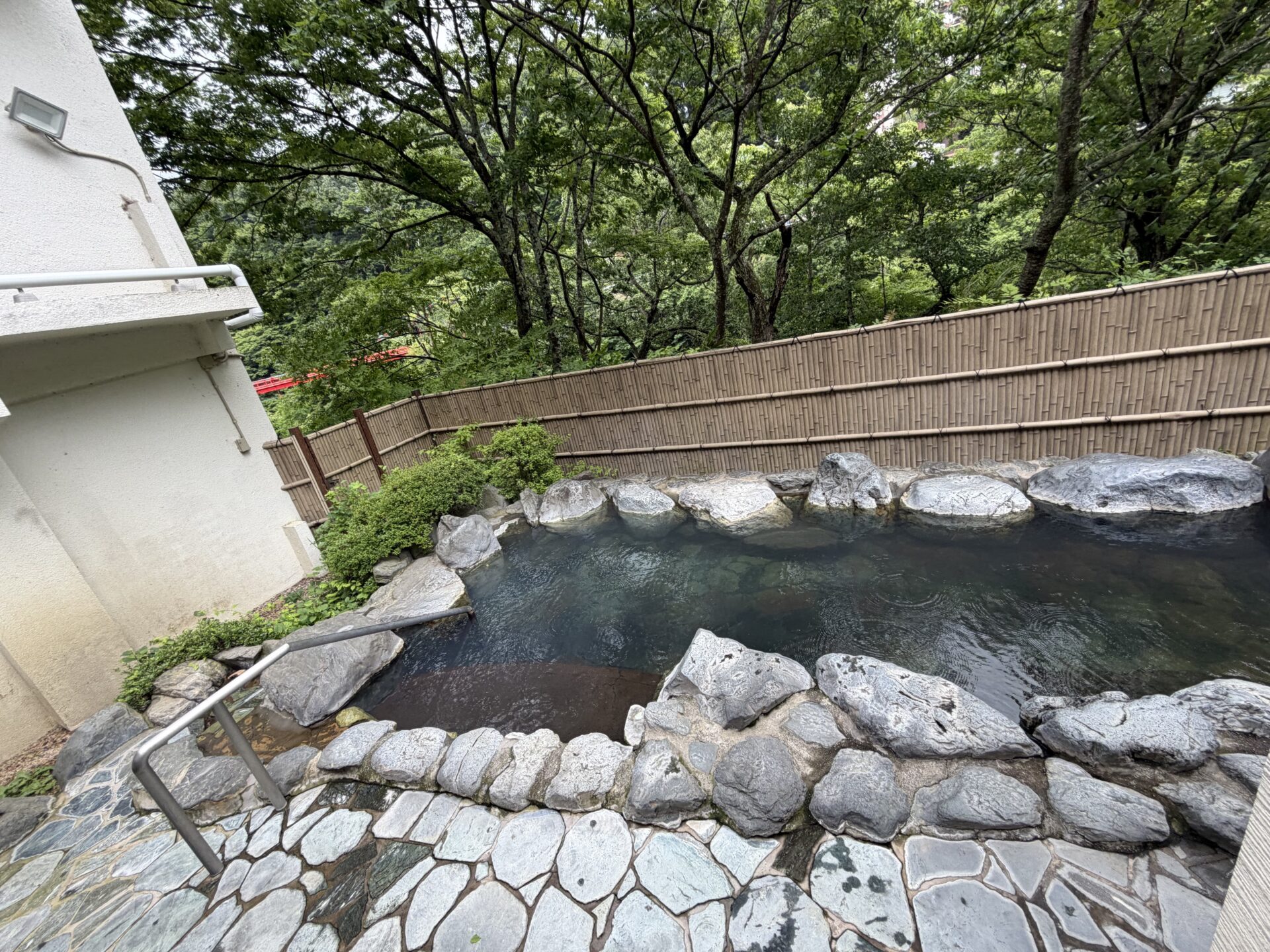 露天風呂「吹割の湯」。岩組みの湯船と竹垣、まわりは渓谷の緑