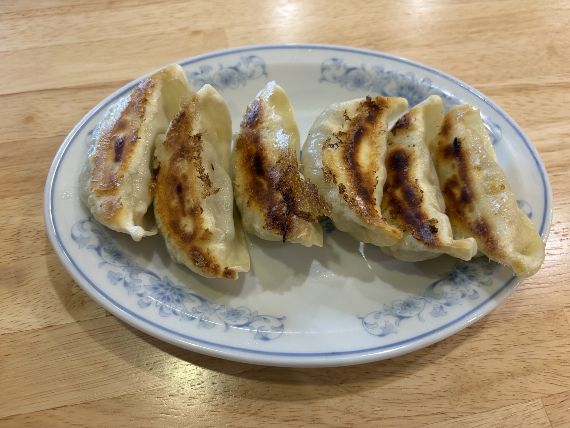 焼餃子。こんがり焼き目のついた、ふっくら大ぶりの餃子が皿に並ぶ