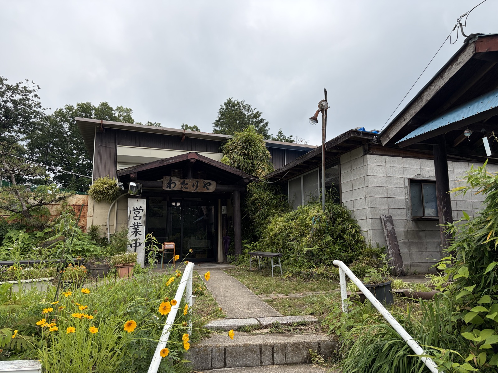 山あいに建つわたりやの外観（営業中の札）