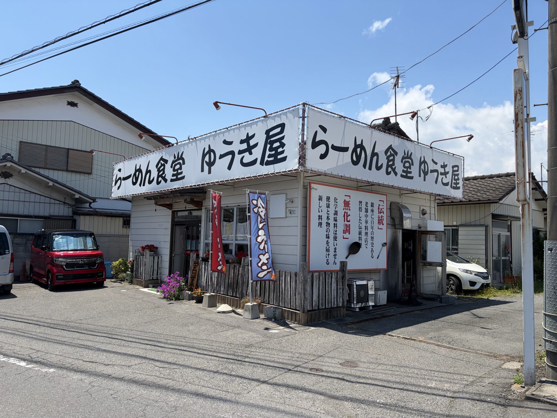 らーめん食堂 ゆうき屋の外観。白い大きな看板と冷やしラーメンののぼり