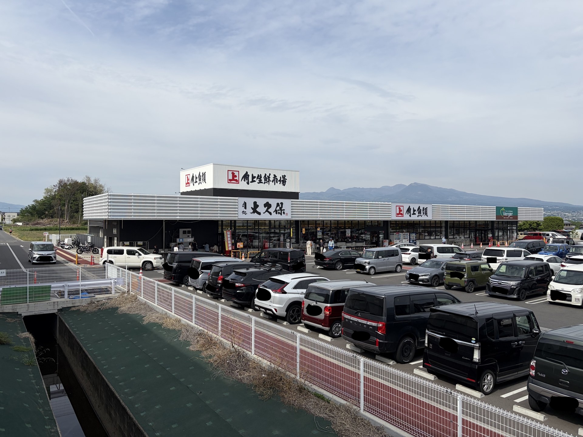 角上魚類 前橋店の外観と満車の駐車場、赤城山系の遠景