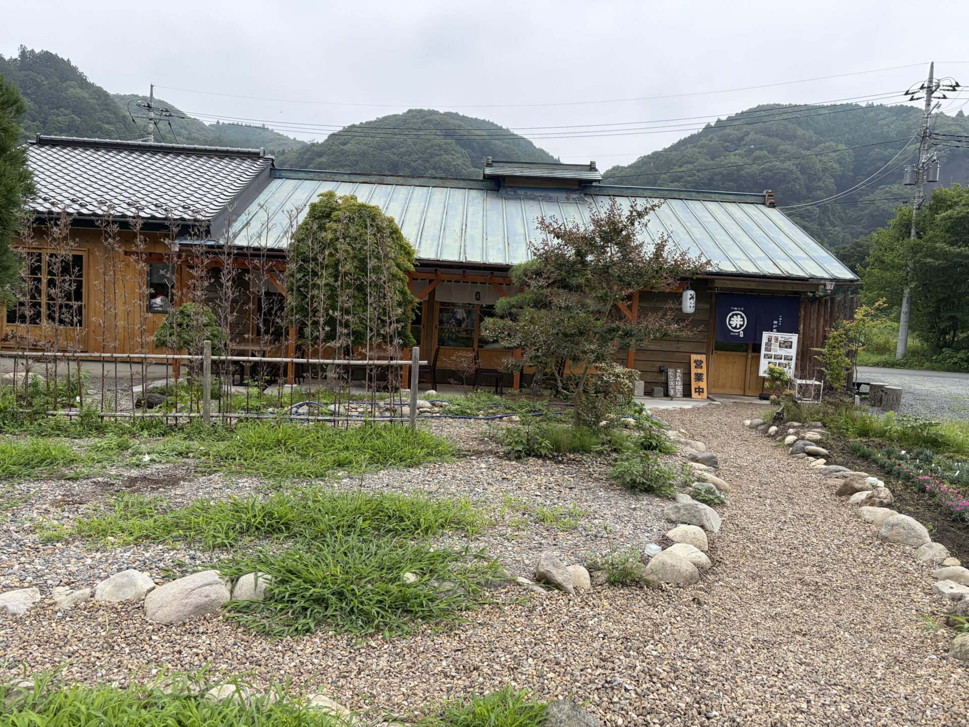 十割そば囲炉裏 水沼店の外観。枯山水風の庭と、緑の山を背にした古民家
