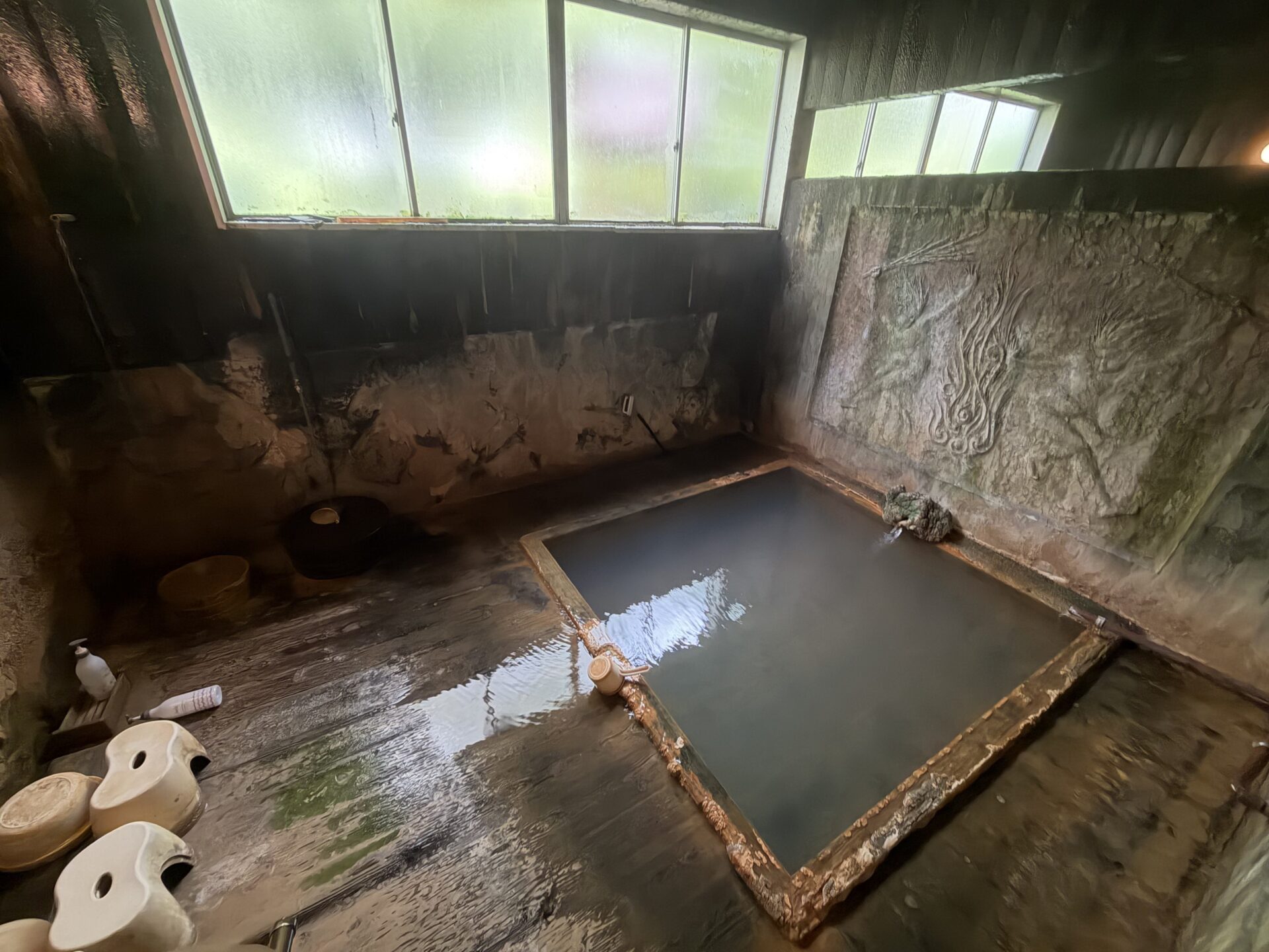 湯船（雲井の湯）。青みがかった灰色に濁り、木の縁は析出でごつごつ
