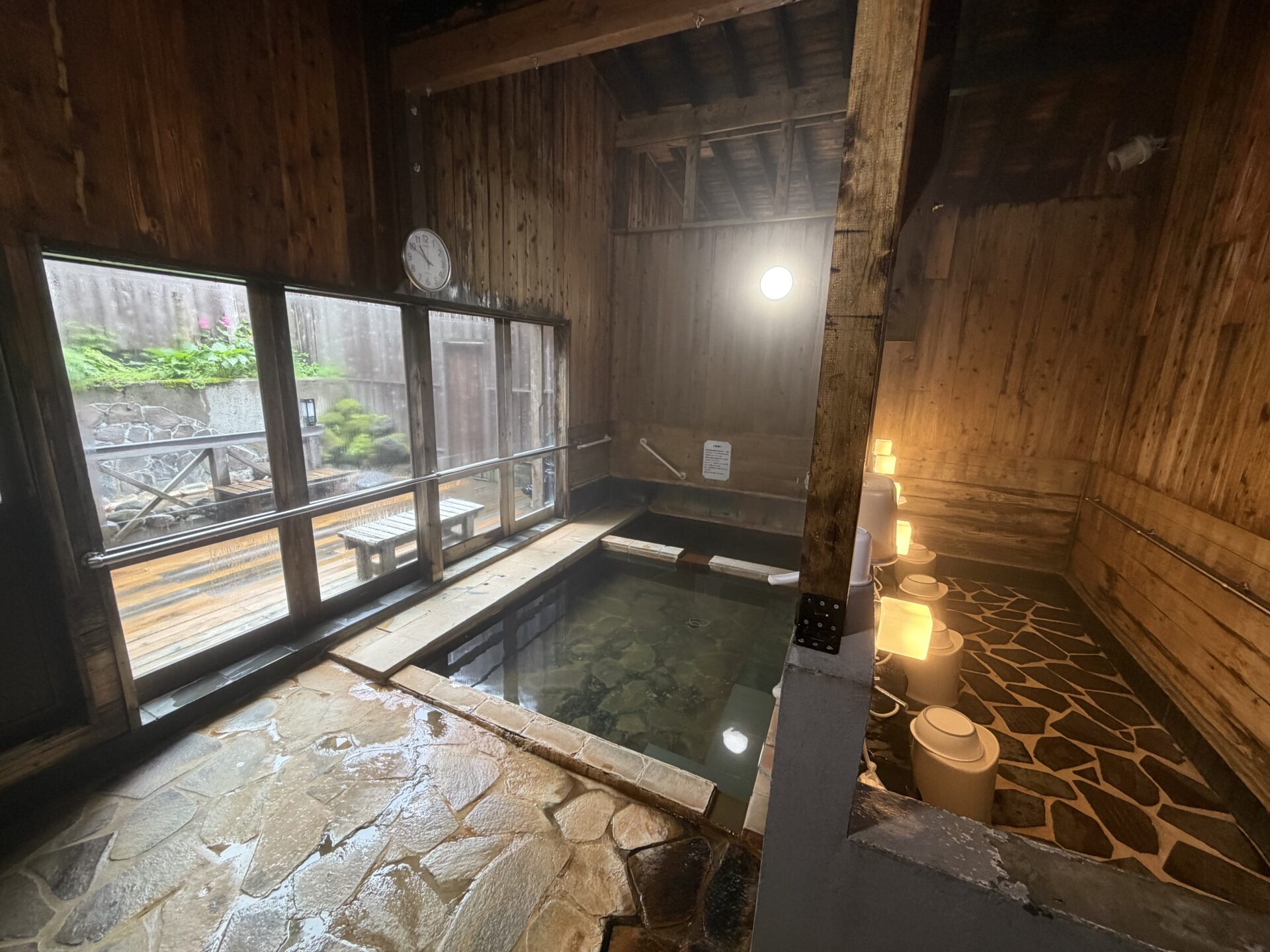 内湯。石張りの浴室で、窓の外に露天と庭がのぞく