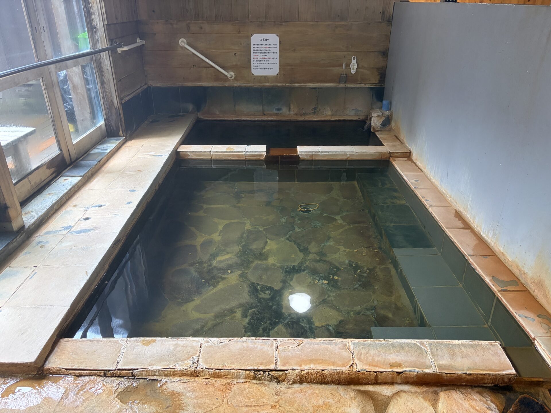 内湯の浴槽。石を組んだ底が湯を通して透ける