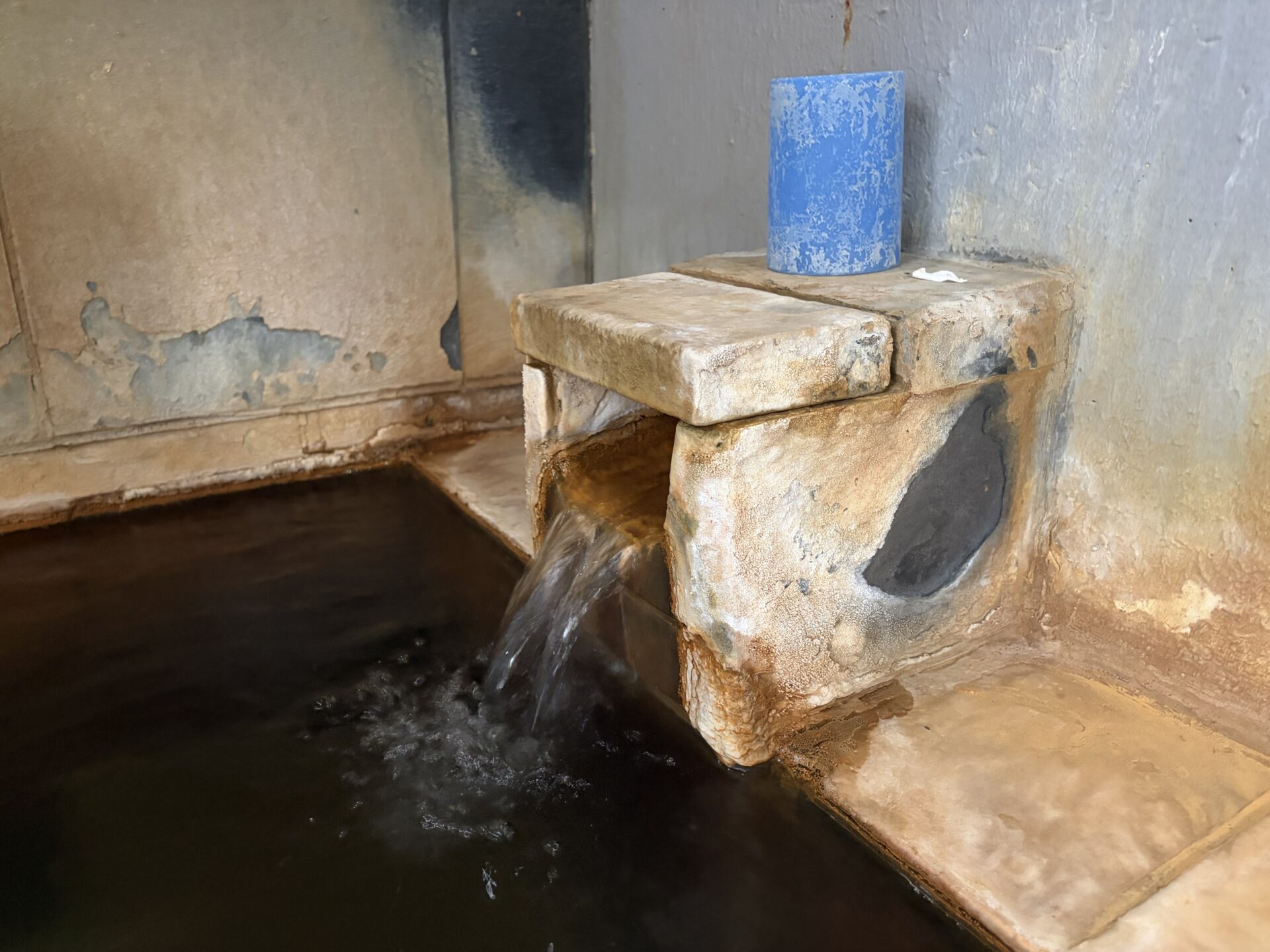 内湯の石の湯口。まわりに成分の析出がこびりつく