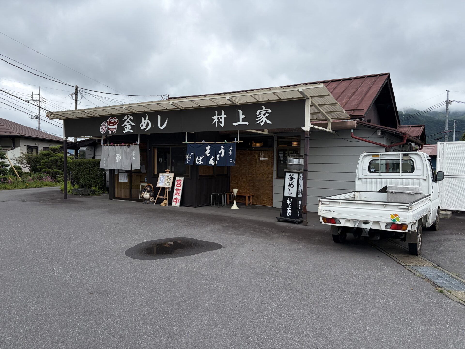 釜めし村上家の外観。黒い看板に「釜めし」「村上家」、営業中の札