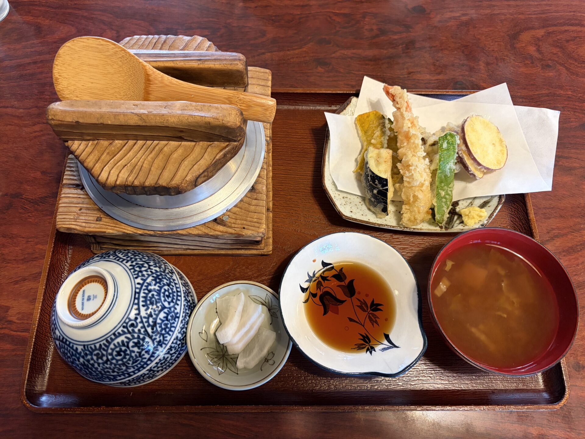 山菜釜飯の天ぷらセット。木の台に載った釜、えびと野菜の天ぷら、味噌汁、お新香、つゆ