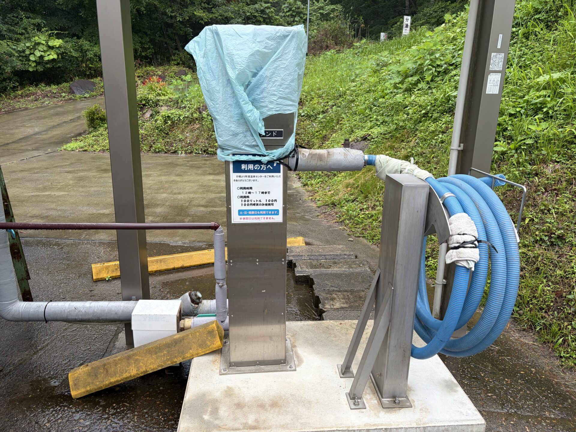 三峰の湯の隣にある温泉スタンド。ステンレスの給湯機に青いホースが一本