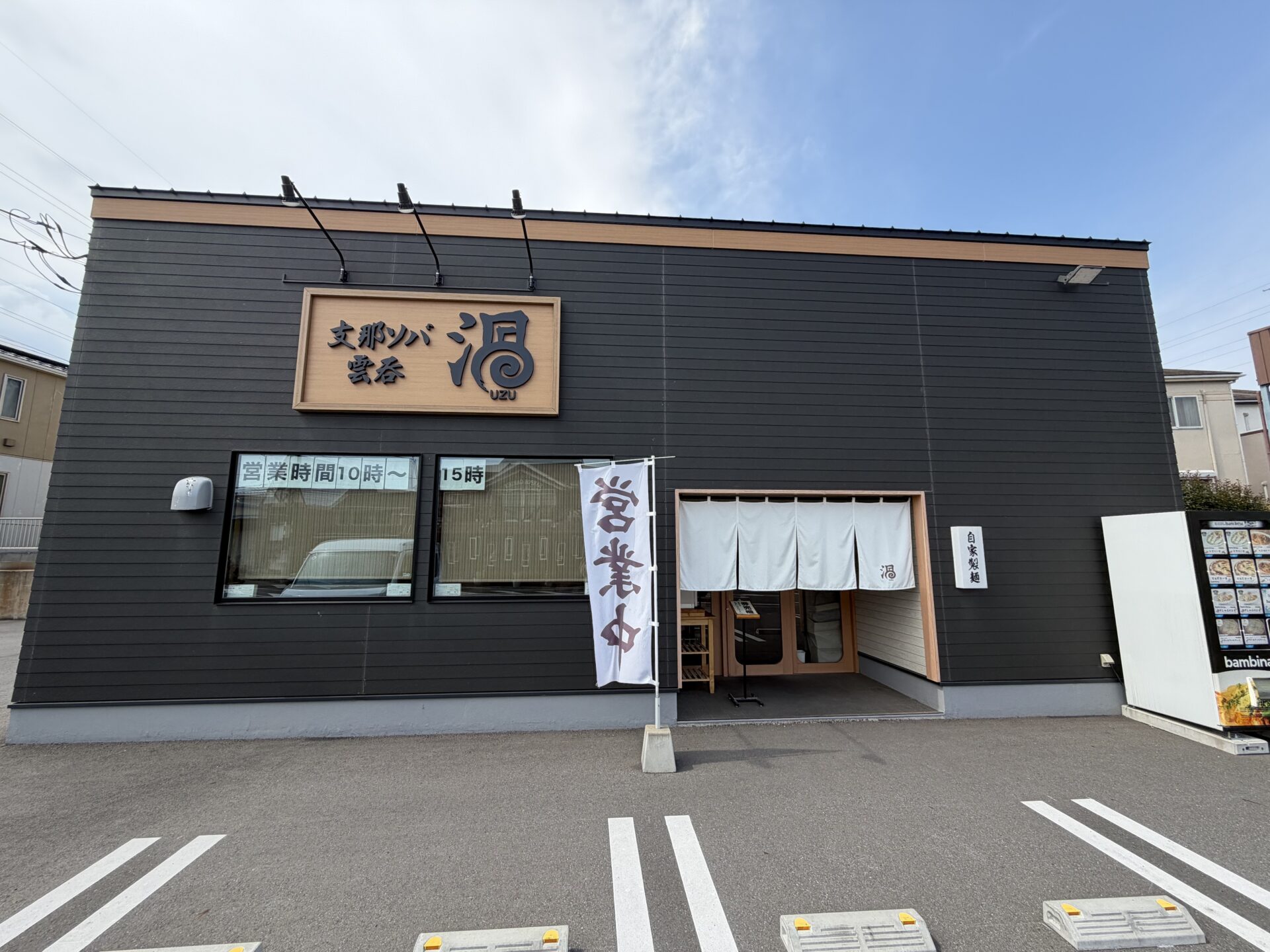 支那ソバ雲呑渦の外観。黒い外壁に木彫りの看板、入口には白いのれんと「自家製麺」の木札