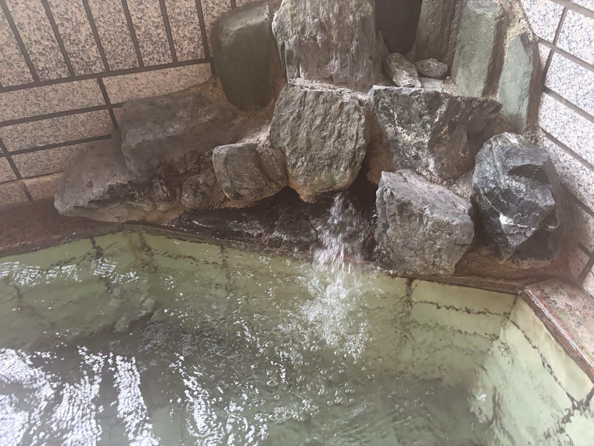 内湯の岩の湯口。岩の間から湯が注ぎ込み、縁に温泉成分が付着している