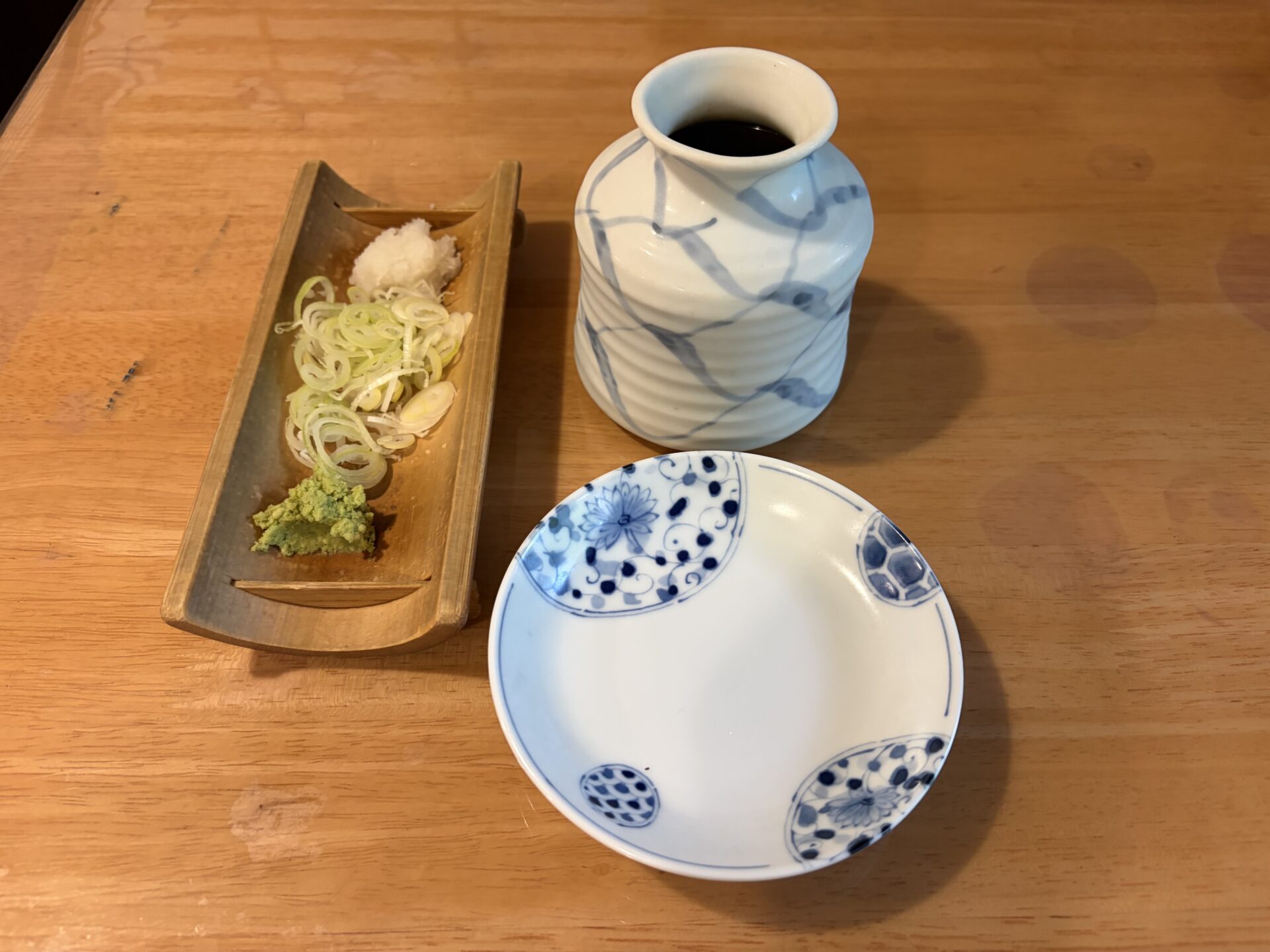 薬味のわさび・刻みねぎ・大根おろしを載せた竹の器と、そばつゆの徳利、取り皿