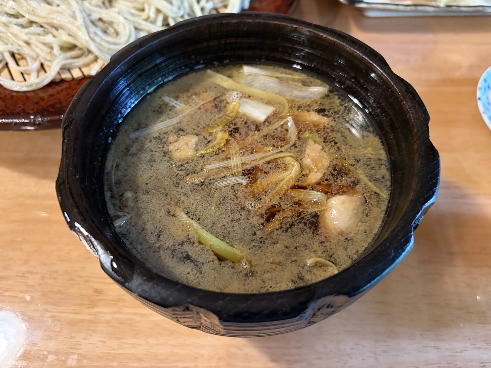 かも汁。黒い汁椀に、鴨肉のぶつ切りと白ねぎ、脂の浮いた温かいつけ汁