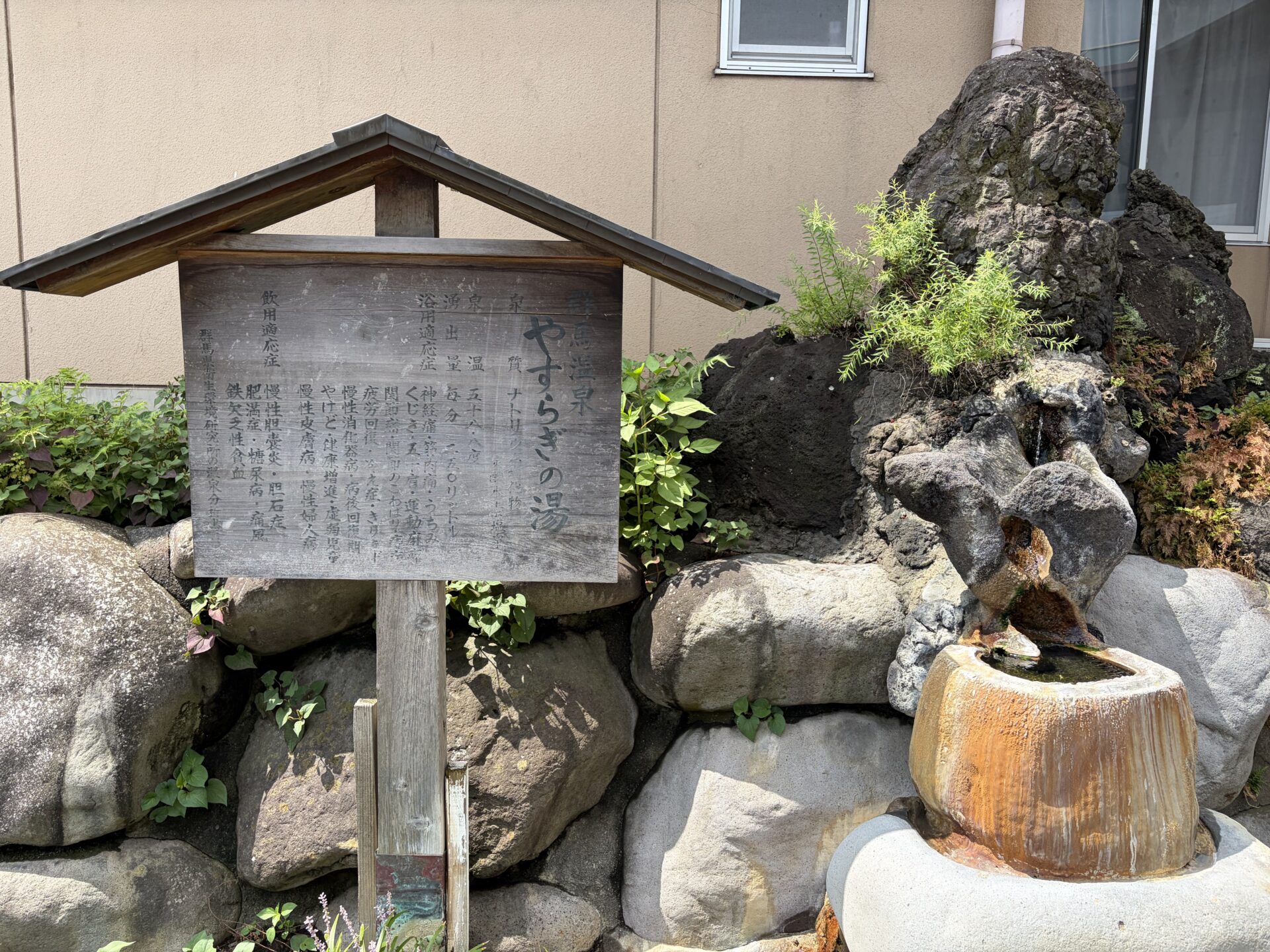 敷地の湯口オブジェ。茶褐色の析出がびっしり付いた鉢が、成分の濃さを外で語っている