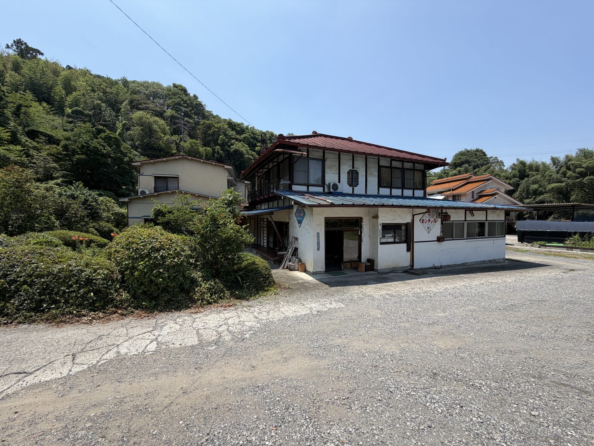青いトタン屋根と「金鳥・キンチョール」のホーロー看板が残る、大島鉱泉の昭和な建物外観