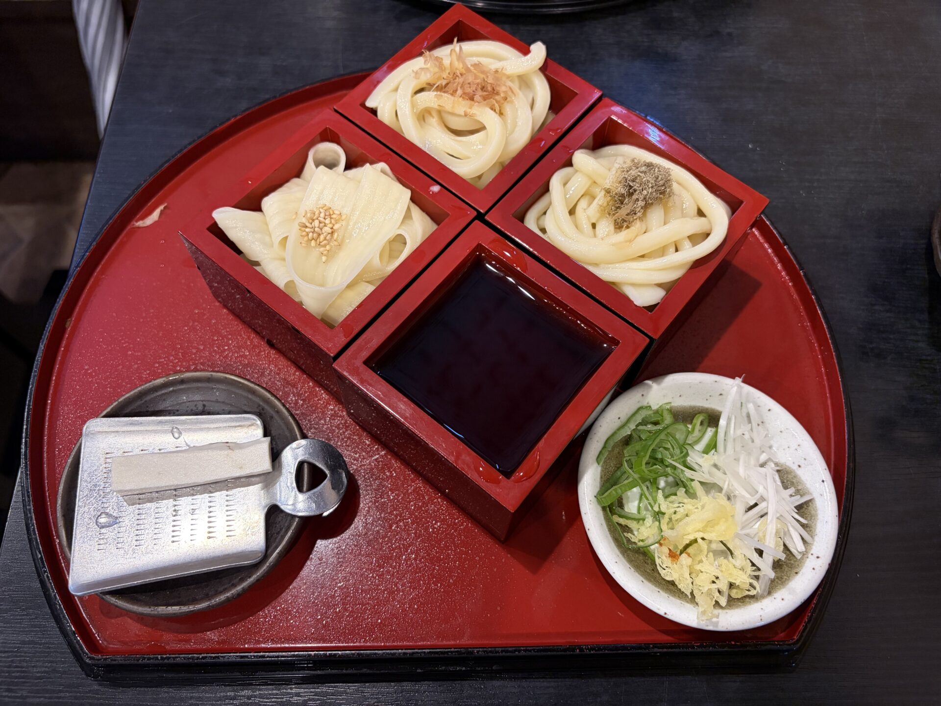 群馬三大うどん食べ比べセット。三色の升に3種のうどんが盛られ、つけ汁と薬味、山わさびをおろすおろし金が添えられている