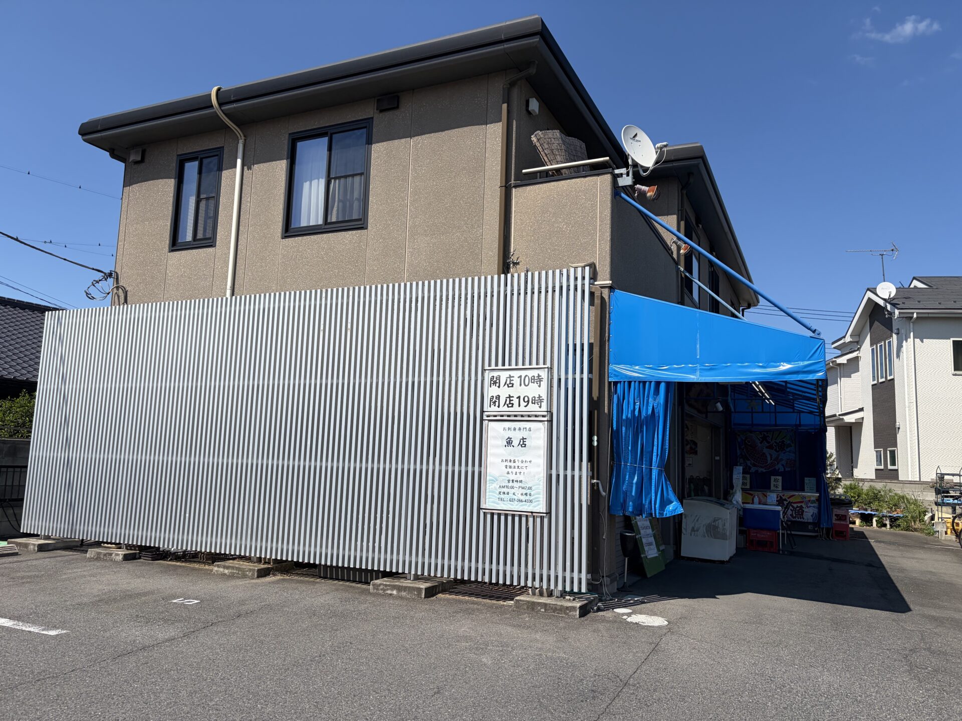 外観。住宅街の中、青いテントの売場入口。店前が駐車場
