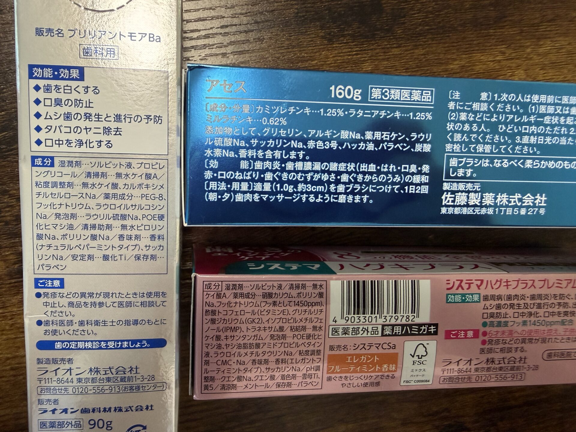 新体制3本の裏面。ハグキプラス プレミアムには「フッ素として1450ppm」、アセスにはハーブチンキ3種の分量が明記されている。効能の文字ではなく、この欄を見る