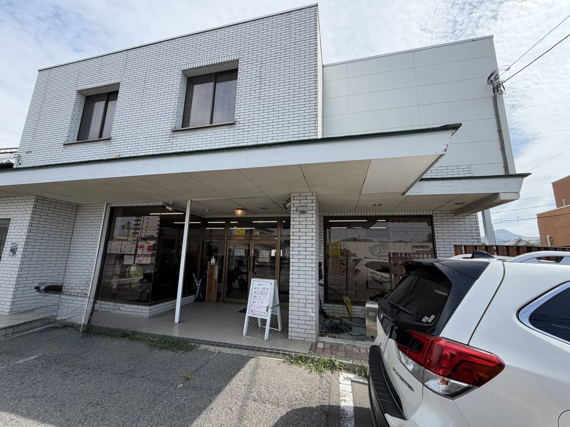 白タイルの店構え。入口前に本日のメニュー看板、ガラスには煮干しの魚が泳ぐ