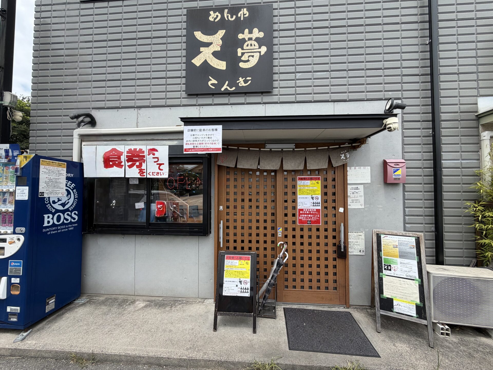 めんや天夢の外観。黒い看板に「めんや天夢 てんむ」、入口には食券の案内