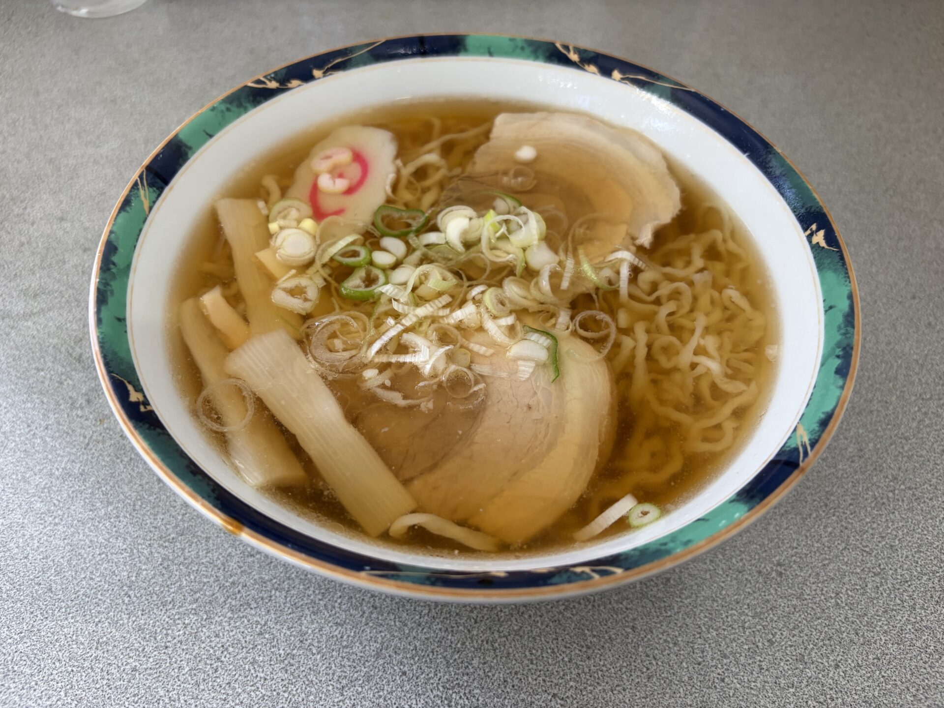 らーめん。黄金色の澄んだスープに不揃いに縮れた自家製麺