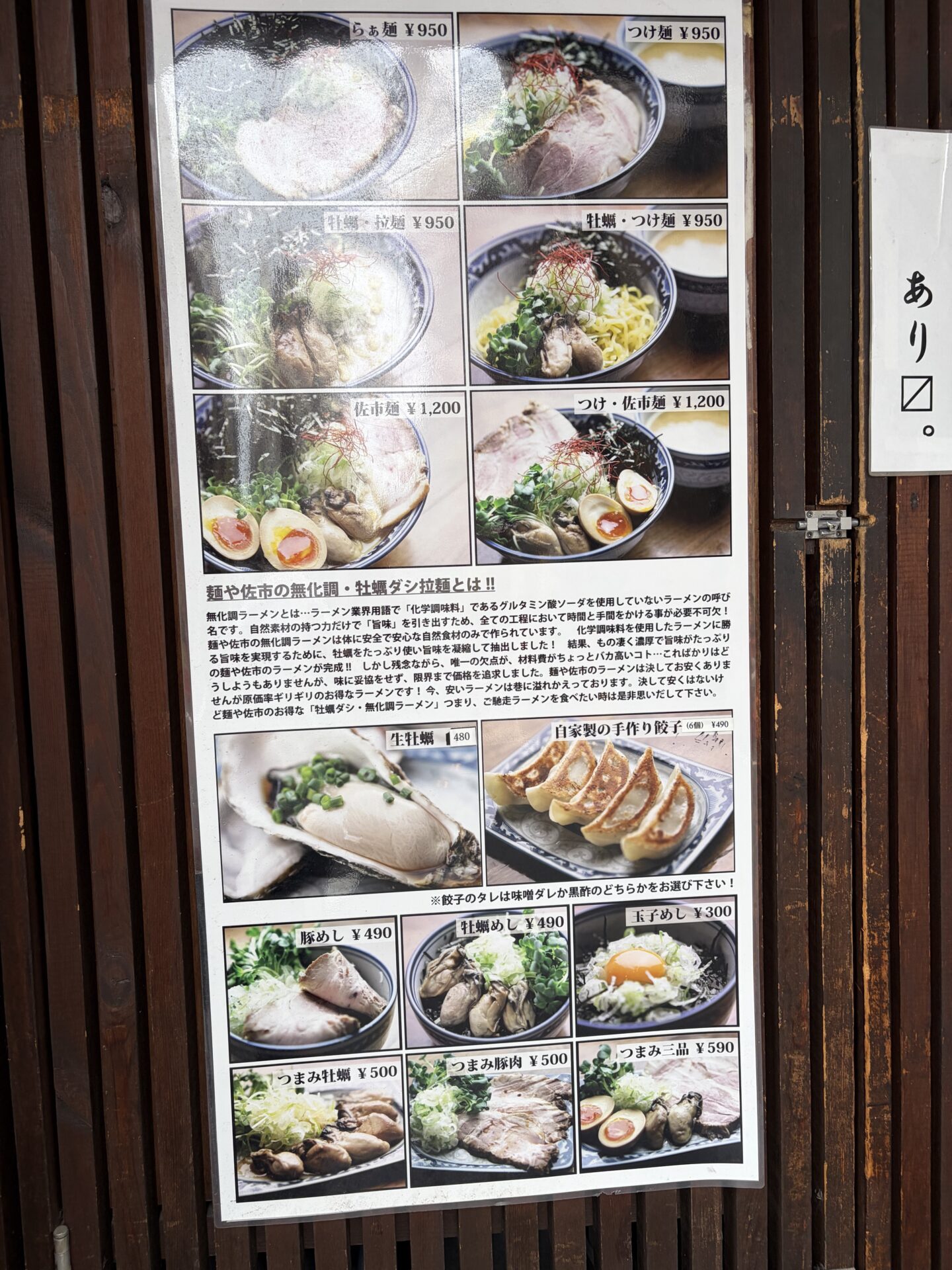 店頭のメニューボード。ラーメンは6種(らぁ麺・つけ麺 各¥950〜佐市麺¥1,200)、サイドに生牡蠣¥480・牡蠣めし¥490・自家製餃子¥490など。「麺や佐市の無化調・牡蠣ダシ拉麺とは!!」の口上も貼られている