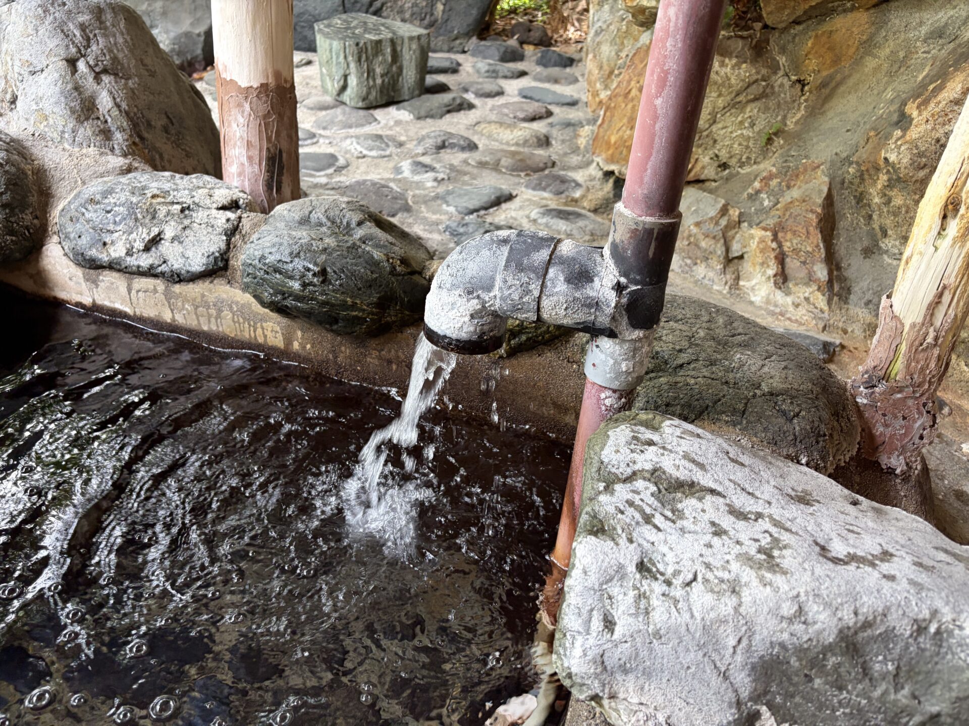 湯口。パイプから落ちた湯が石を伝う
