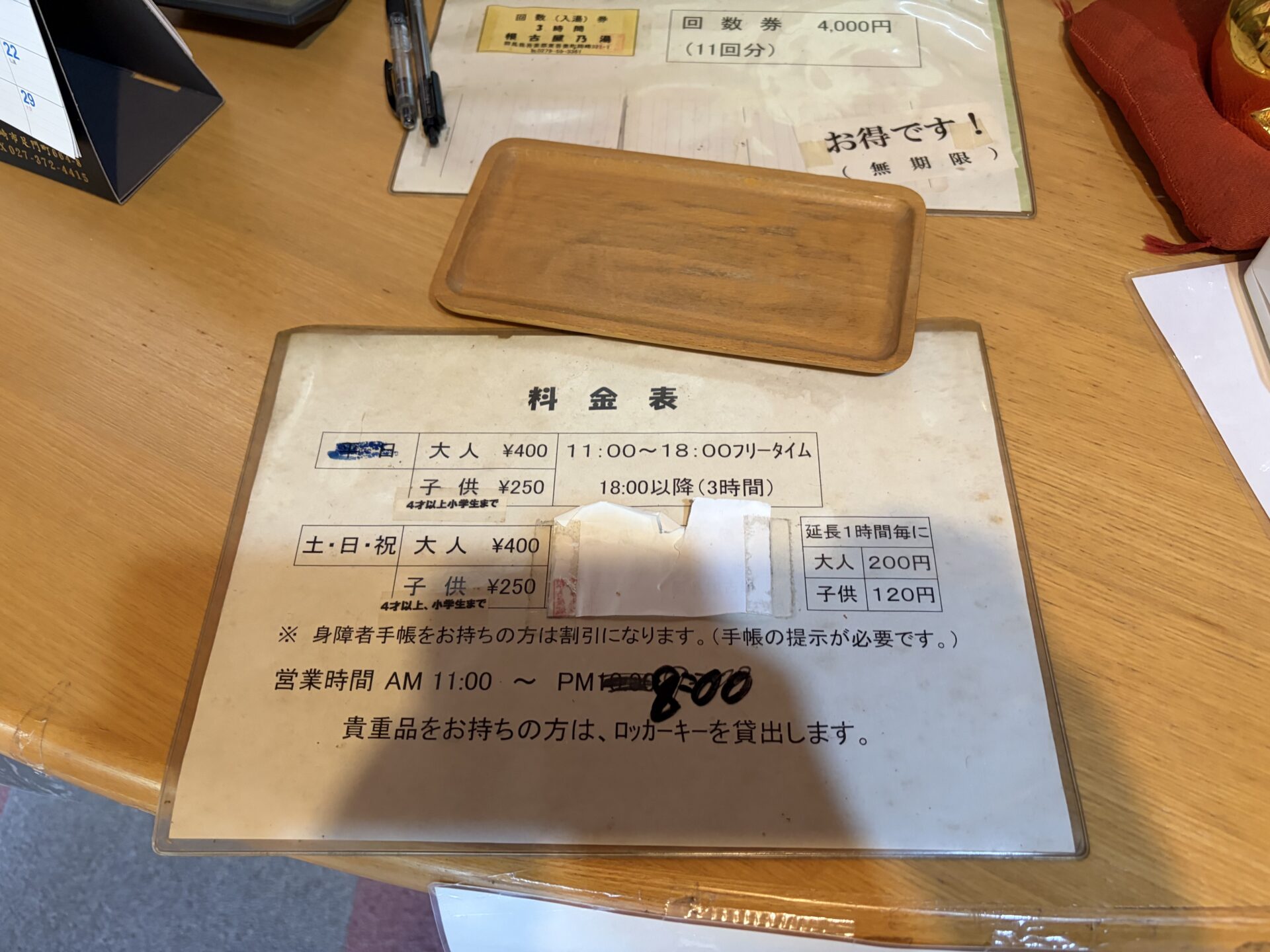 受付の料金表。営業時間のPM10:00に手書きの線が引かれ「8:00」と訂正されている